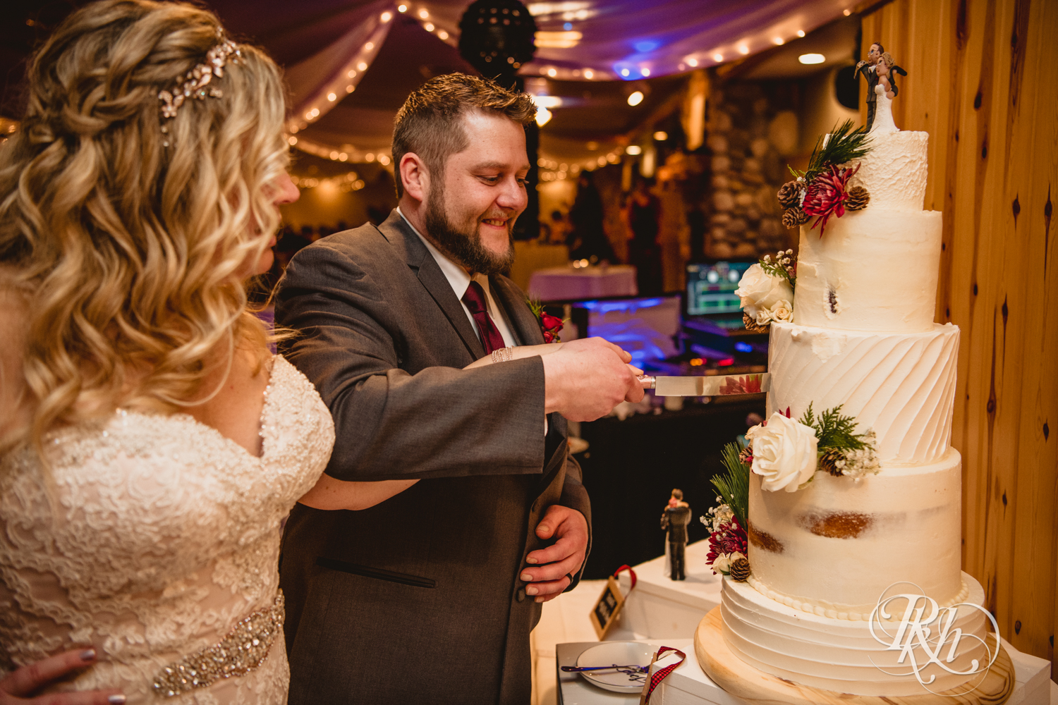 Bride and groom cut cake during winter wedding reception at Whitefish Lodge in Crosslake, Minnesota.