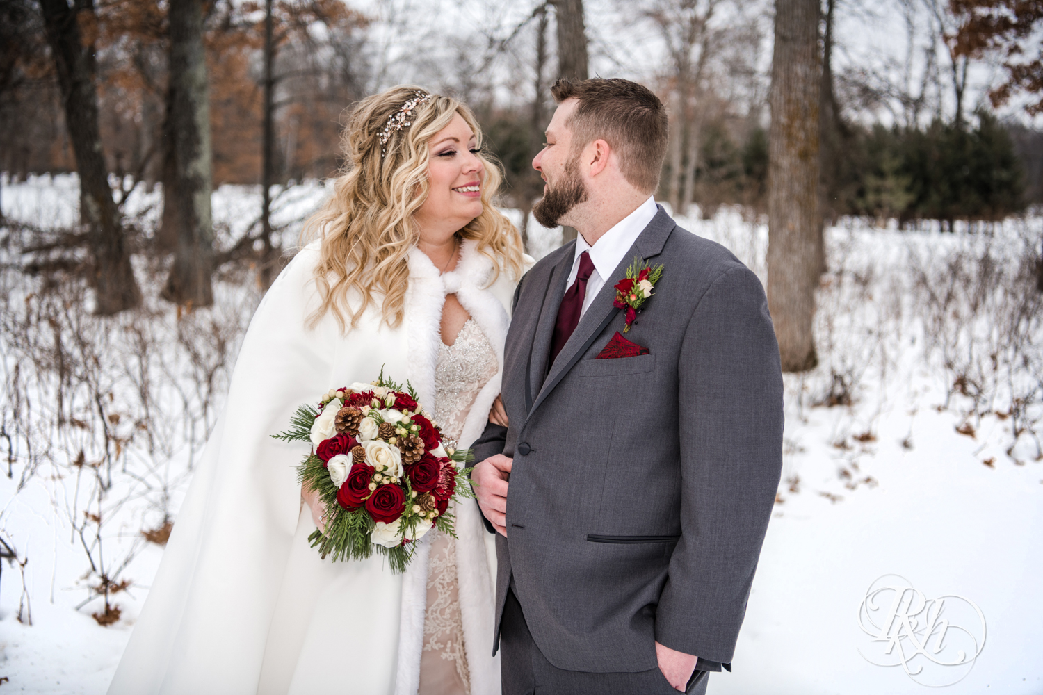 Bride and groom smile in snow during winter wedding at Whitefish Lodge in Crosslake, Minnesota.