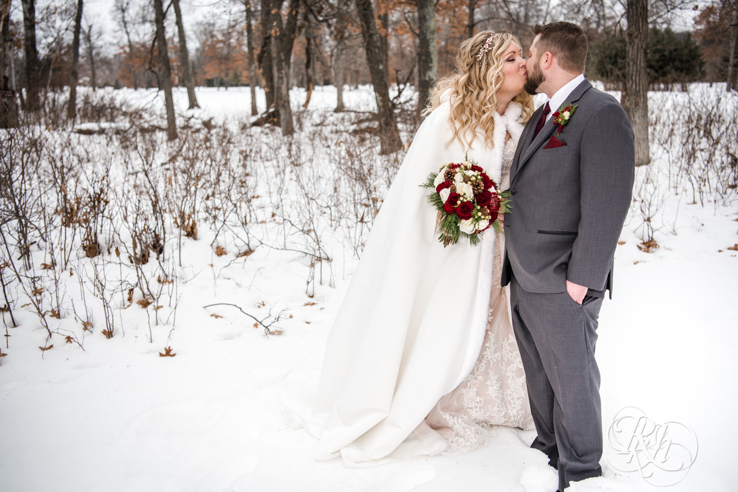 Bride and groom kiss in snow during winter wedding at Whitefish Lodge in Crosslake, Minnesota.