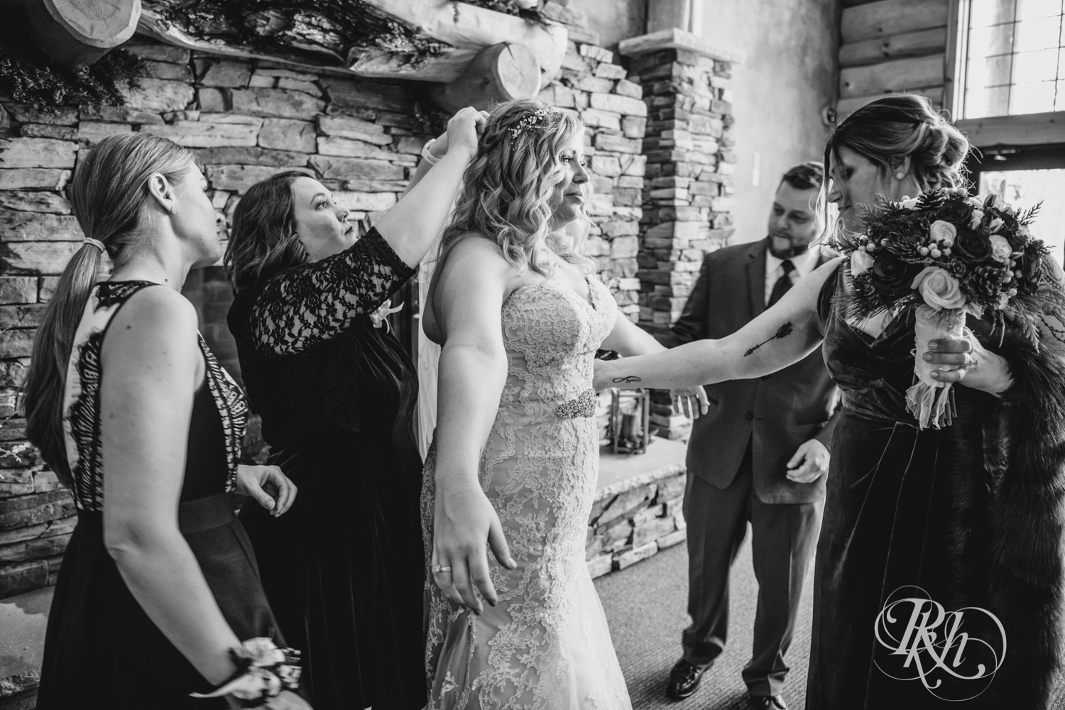 Wedding party helps bride during winter wedding at Whitefish Lodge in Crosslake, Minnesota.