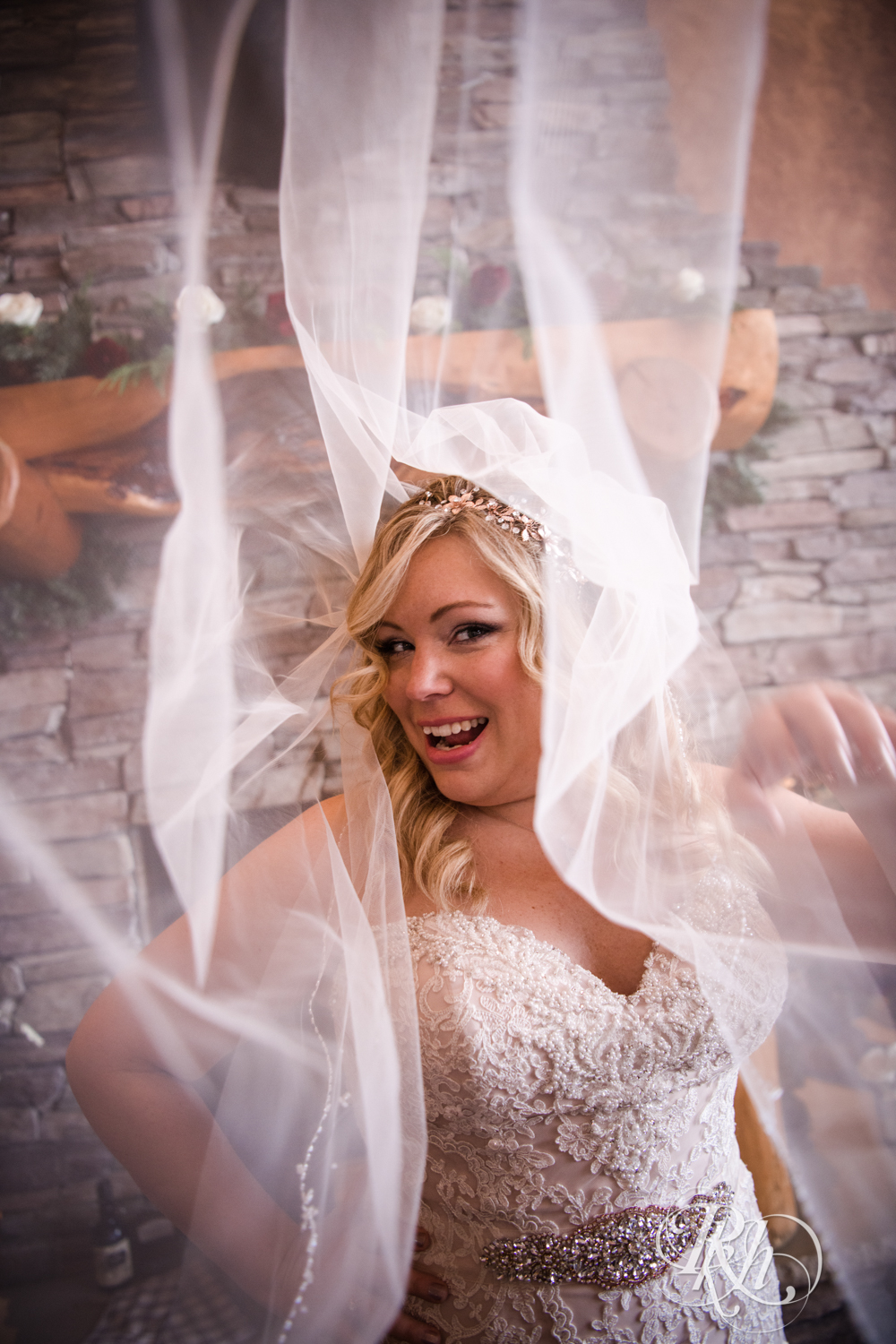 Bride smiles under veil during winter wedding at Whitefish Lodge in Crosslake, Minnesota.