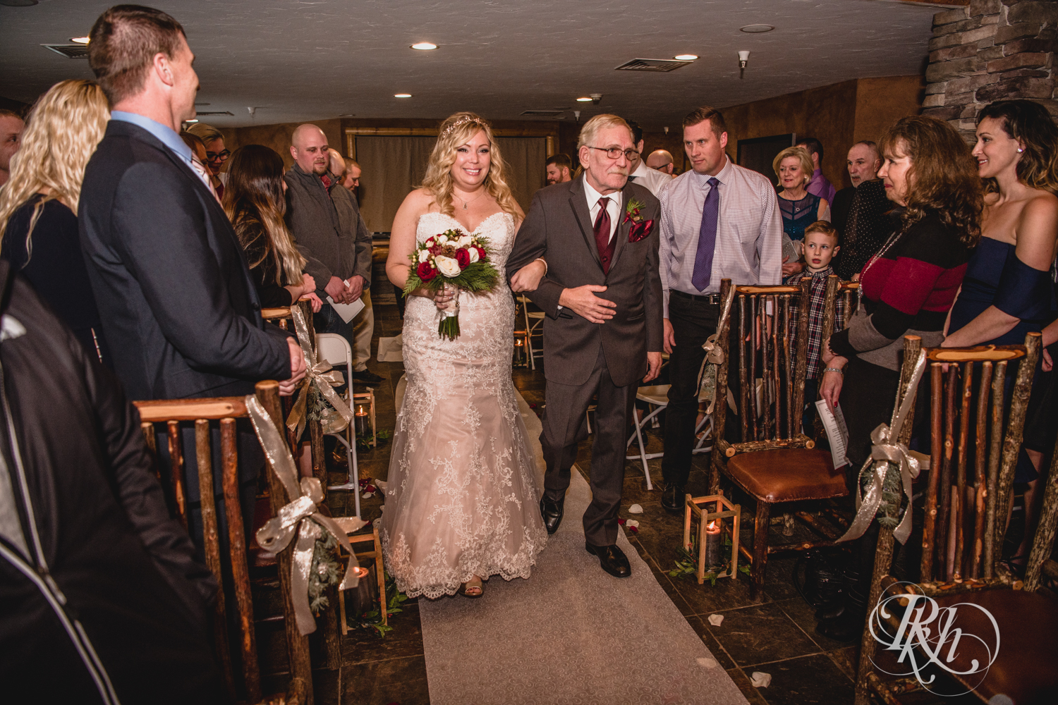 Bride walks down the aisle during winter wedding at Whitefish Lodge in Crosslake, Minnesota.