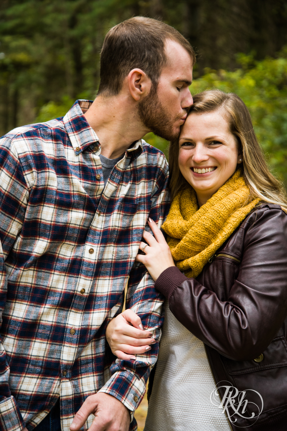 Man in flannel and woman in yellow scarf smile and kiss at Lebanon Hills Regional Park in Eagan, Minnesota.