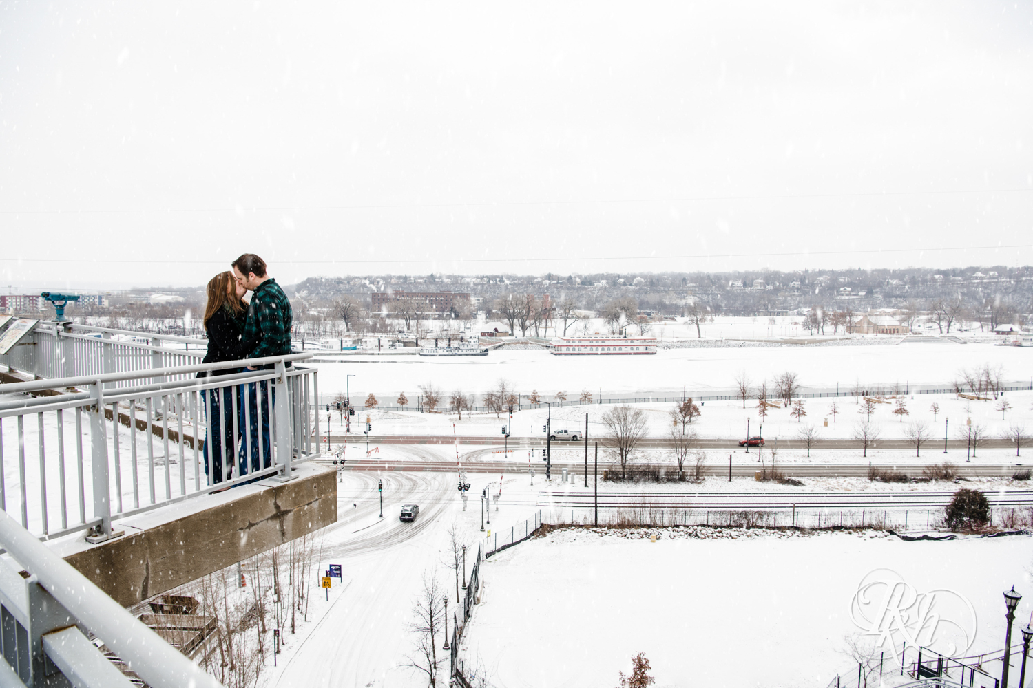 Man and woman kiss in the falling snow during engagement photography in Saint Paul, Minnesota.
