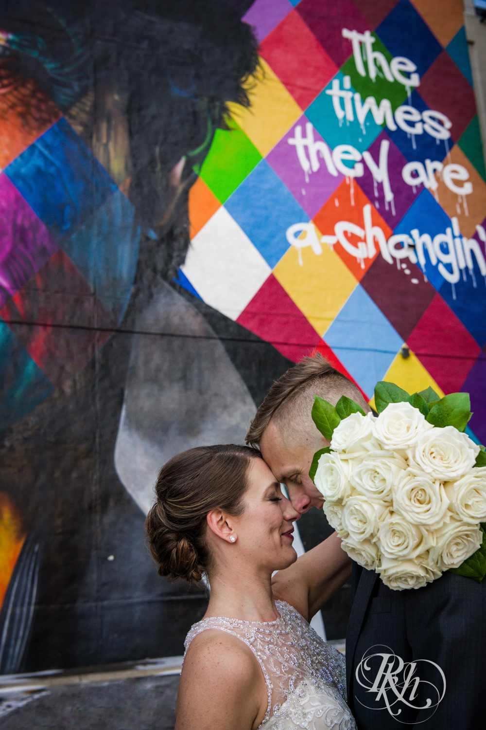 Bride and groom stand in front of the Bob Dylan mural in Minneapolis, Minnesota.