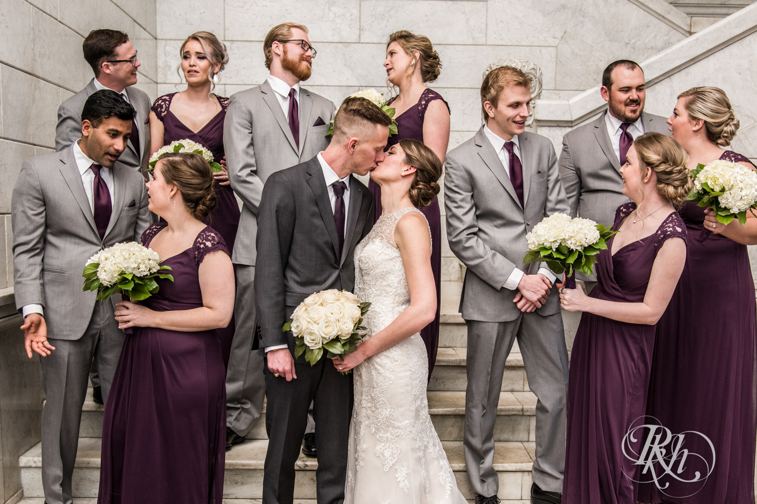 Bride and groom kiss amidst wedding party in the Lumber Exchange Event Center in Minneapolis, Minnesota.