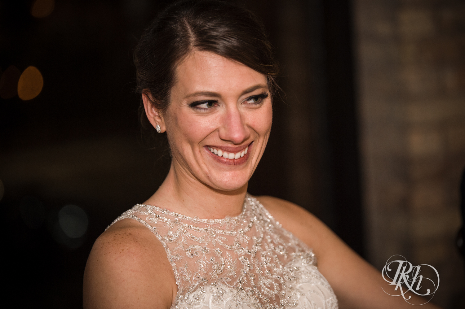 Bride smiles during speeches at wedding reception at the Lumber Exchange Event Center in Minneapolis, Minnesota.