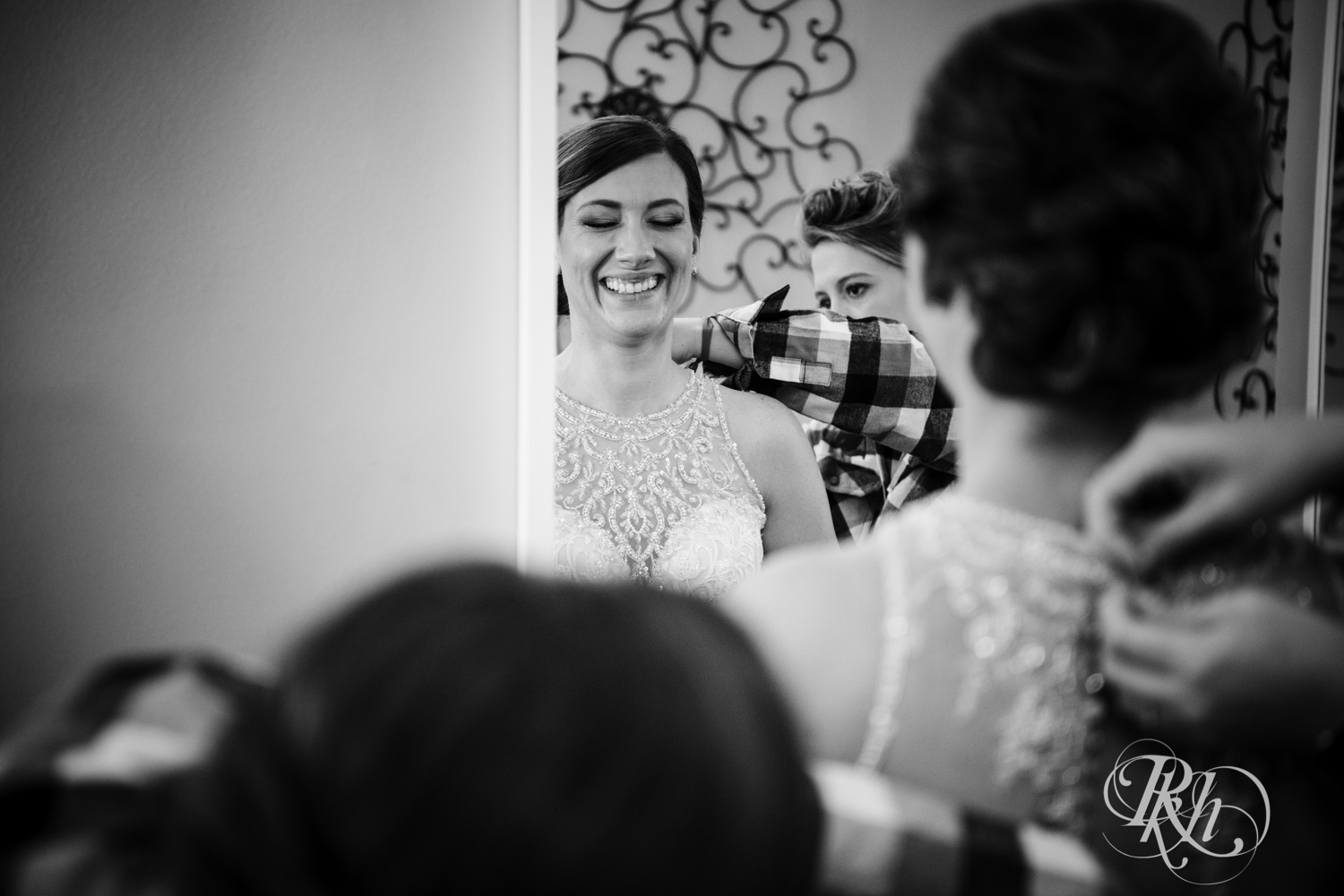 Bride laughs while getting buttoned into wedding dress in the Lumber Exchange Event Center in Minneapolis, Minnesota.