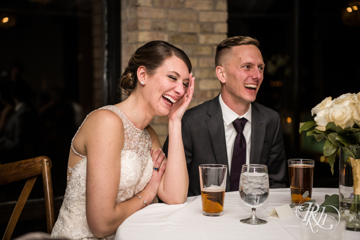 Bride and groom laugh during speeches at wedding reception at the Lumber Exchange Event Center in Minneapolis, Minnesota.