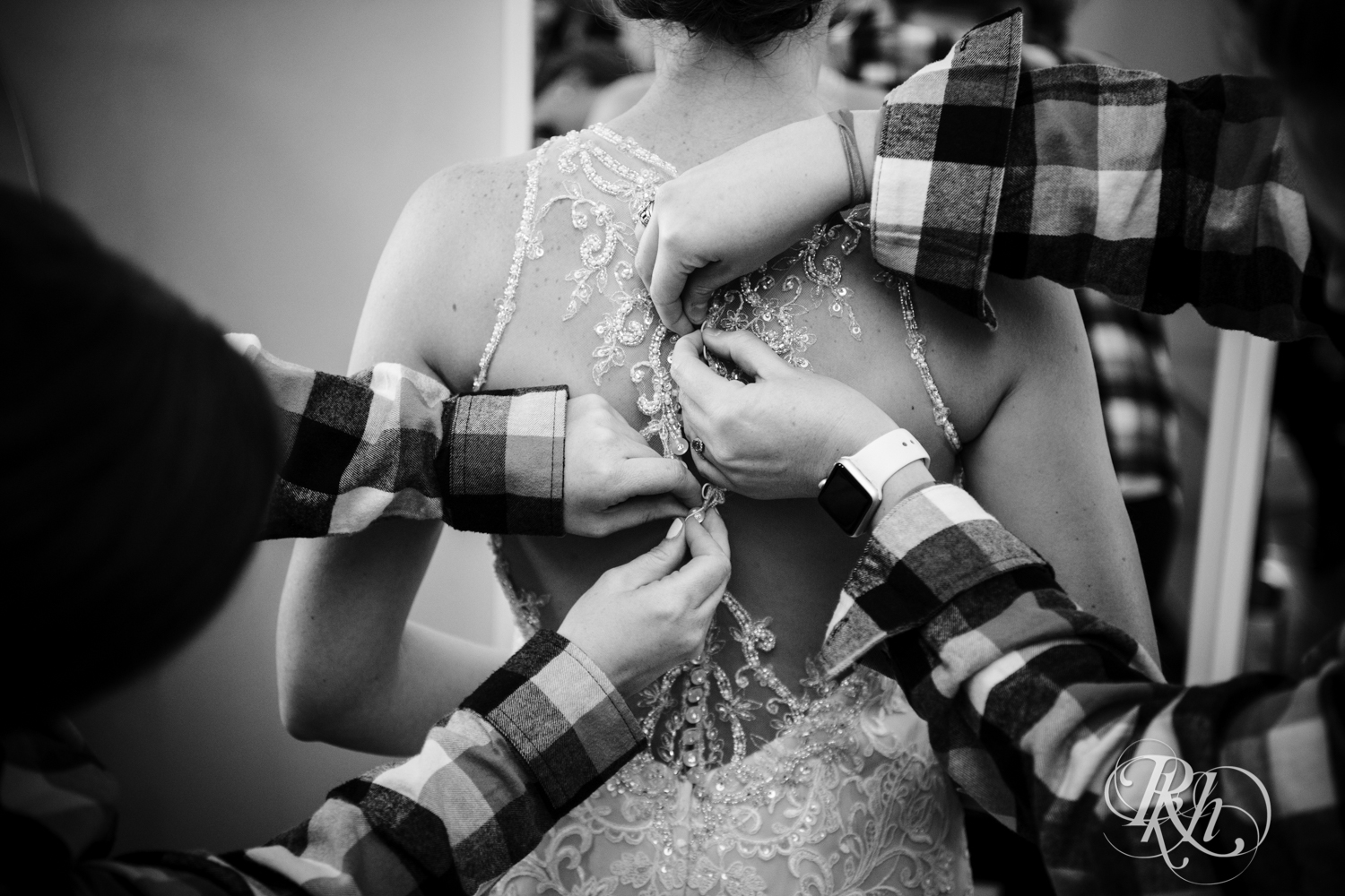 Bridesmaids buttoning bride's dress
