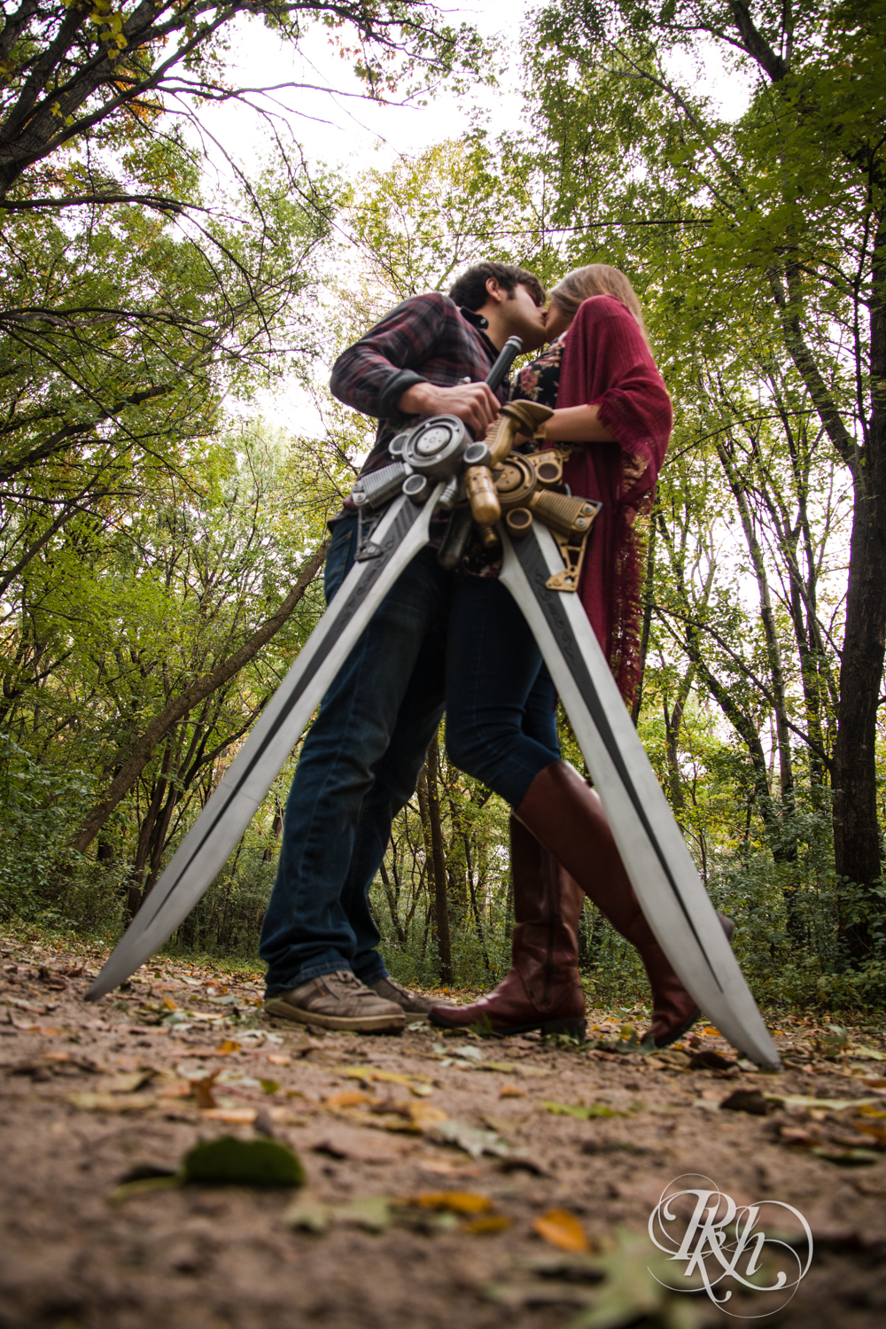 Man and woman kiss during cosplay engagement photography holding swords in Minneapolis, Minnesota.