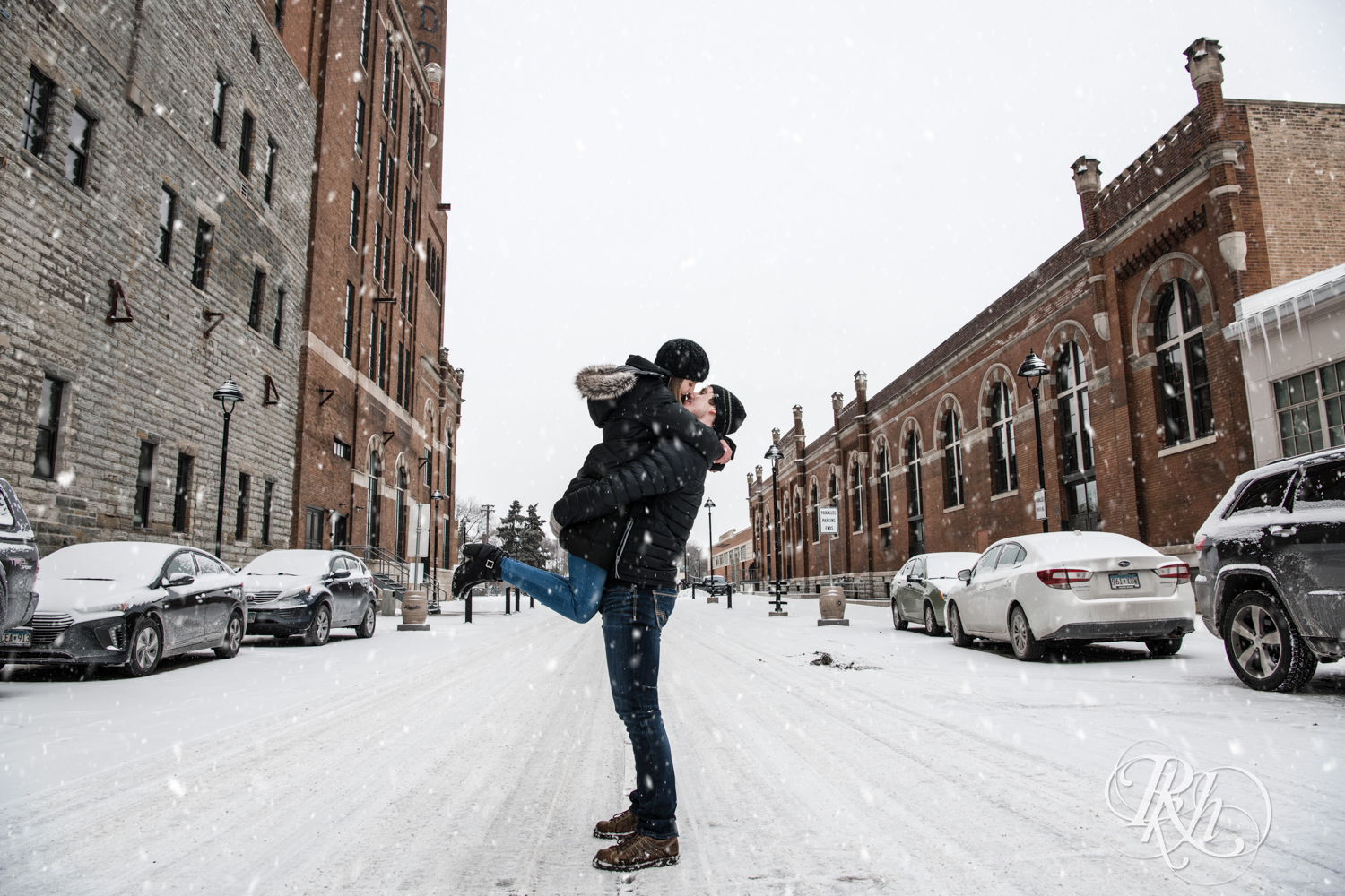 Man and woman kiss in the falling snow during winter engagement photos in Saint Paul, Minnesota.