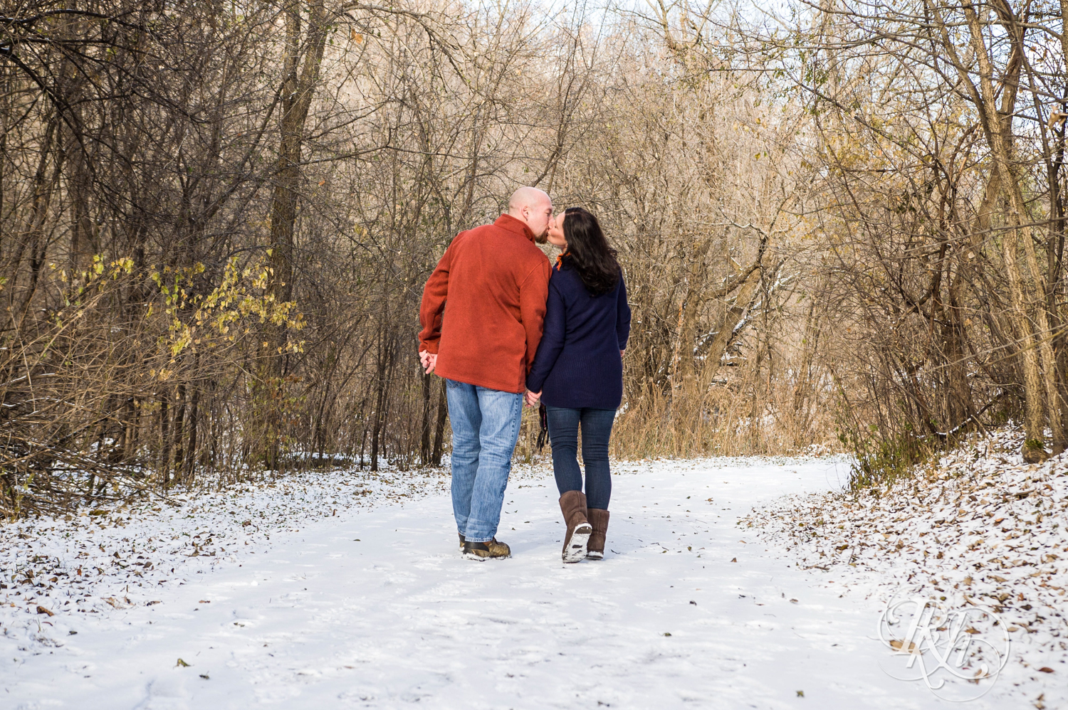 Man and woman kiss while walking in snow in Hidden Valley Park in Savage, Minnesota.