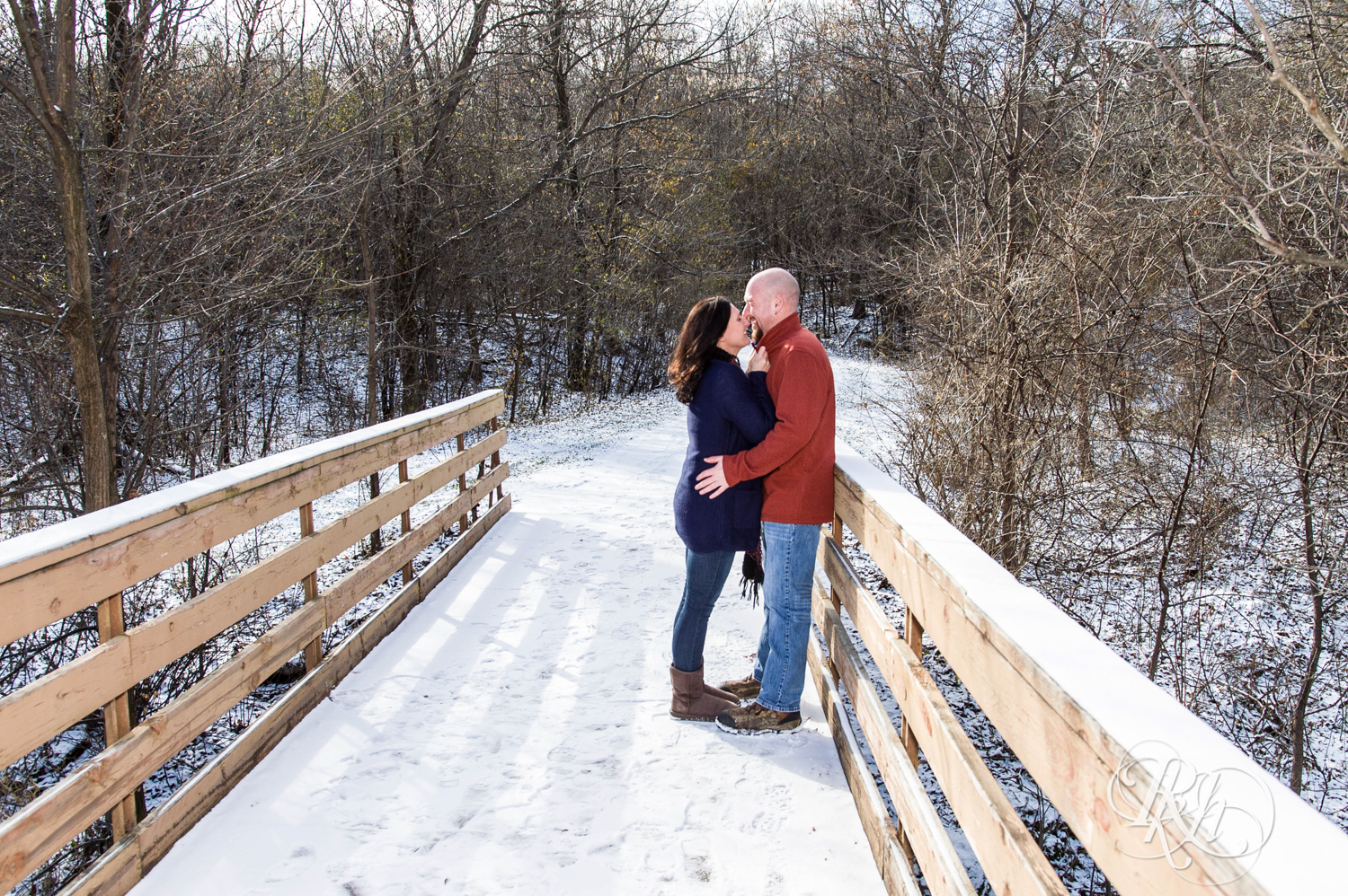 Man and woman kiss on bridge in Hidden Valley Park in Savage, Minnesota.