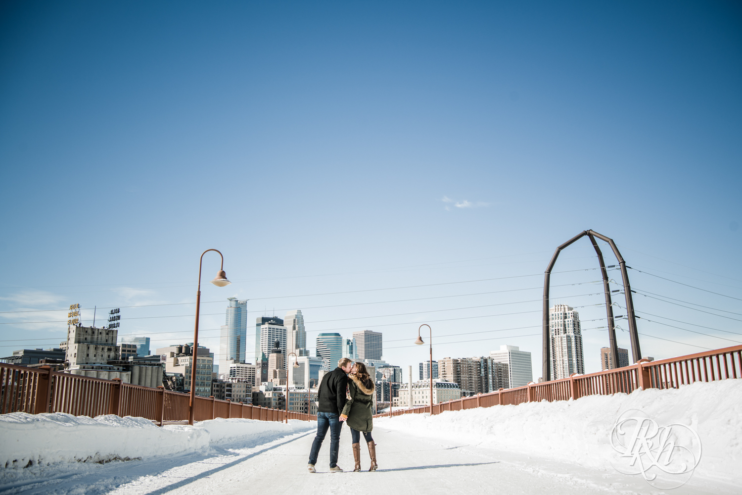 Man and woman kiss during winter engagement photography on the Stone Arch Bridge in Minneapolis, Minnesota.