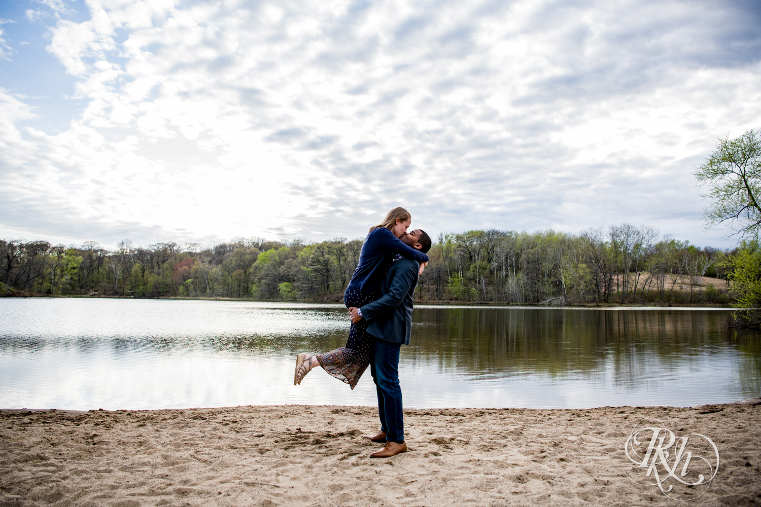 Biracial couple kiss on beach at Lebanon Hills Regional Park in Eagan, Minnesota.
