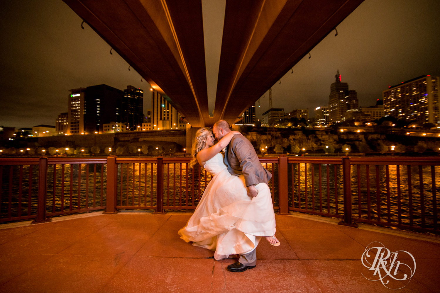 Bride and groom kiss at night at the Minnesota Boat Club on Raspberry Island in Saint Paul, Minnesota.
