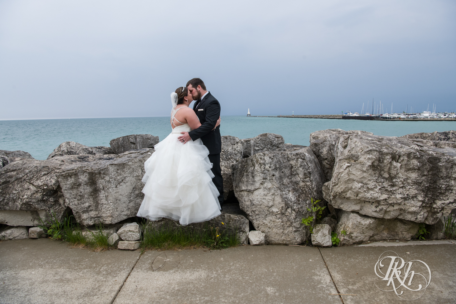 Bride and groom kiss in front of Lake Michigan in Port Washington, Wisconsin