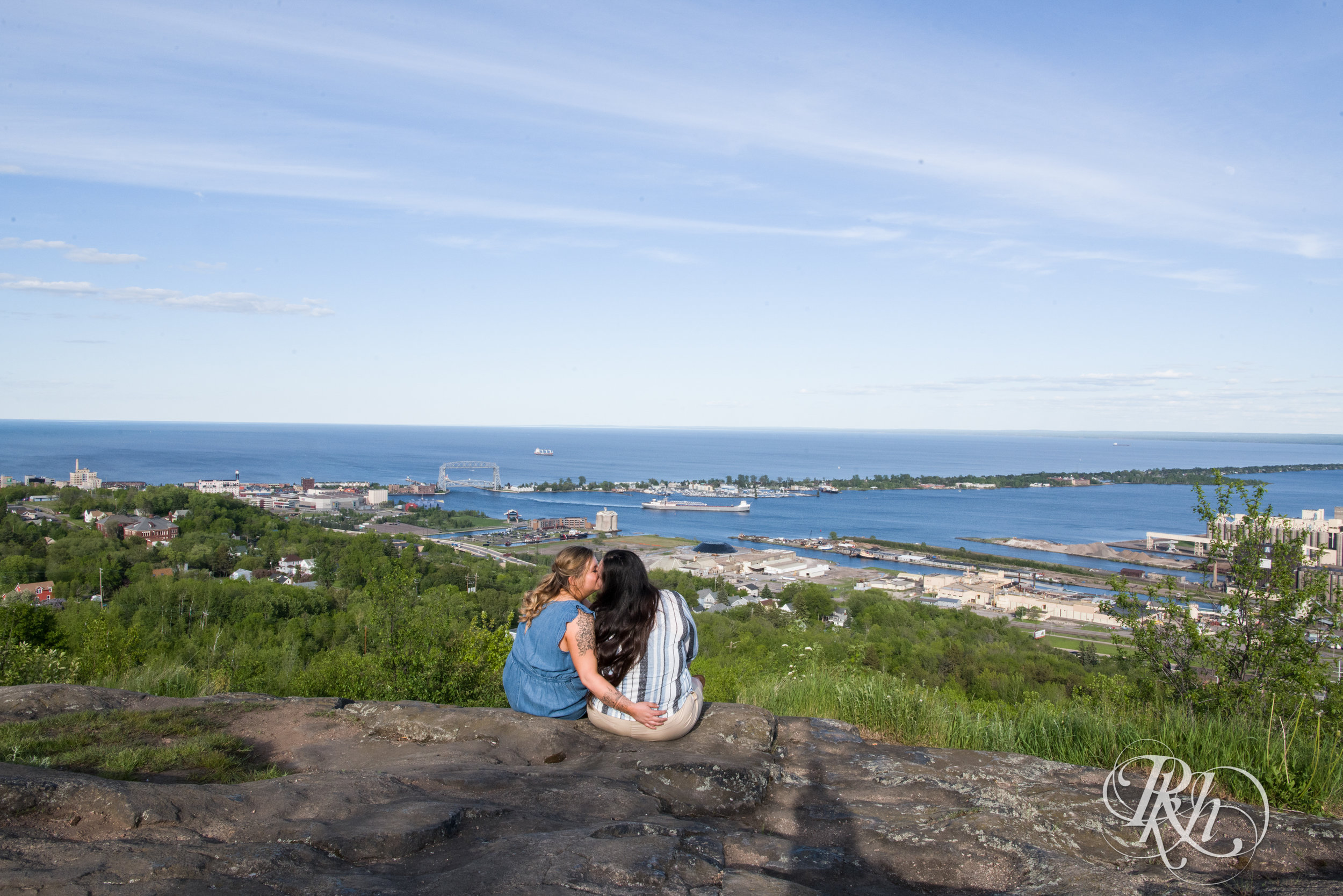 Lesbian couple kiss overlooking Lake Superior during engagement session in Duluth, Minnesota.