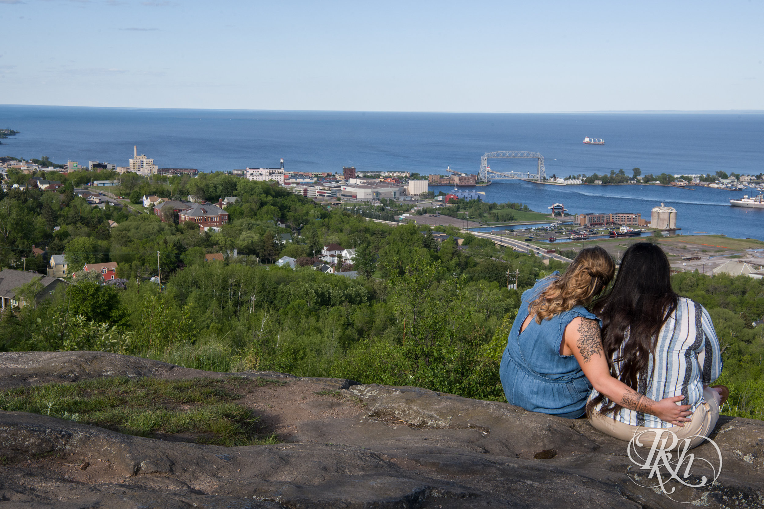 Lesbian couple kiss overlooking Lake Superior during engagement session in Duluth, Minnesota.