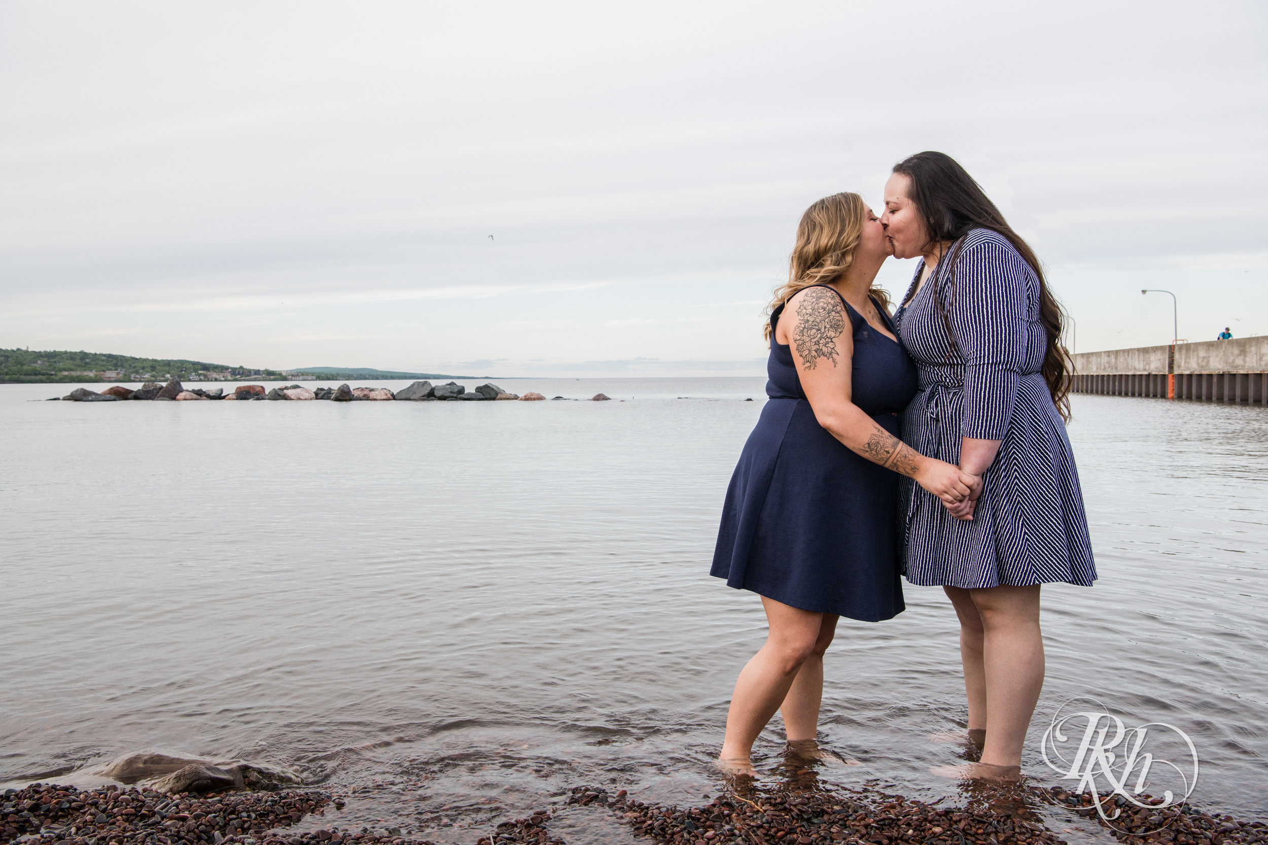 Lesbian couple kiss in Lake Superior during engagement session in Duluth, Minnesota.