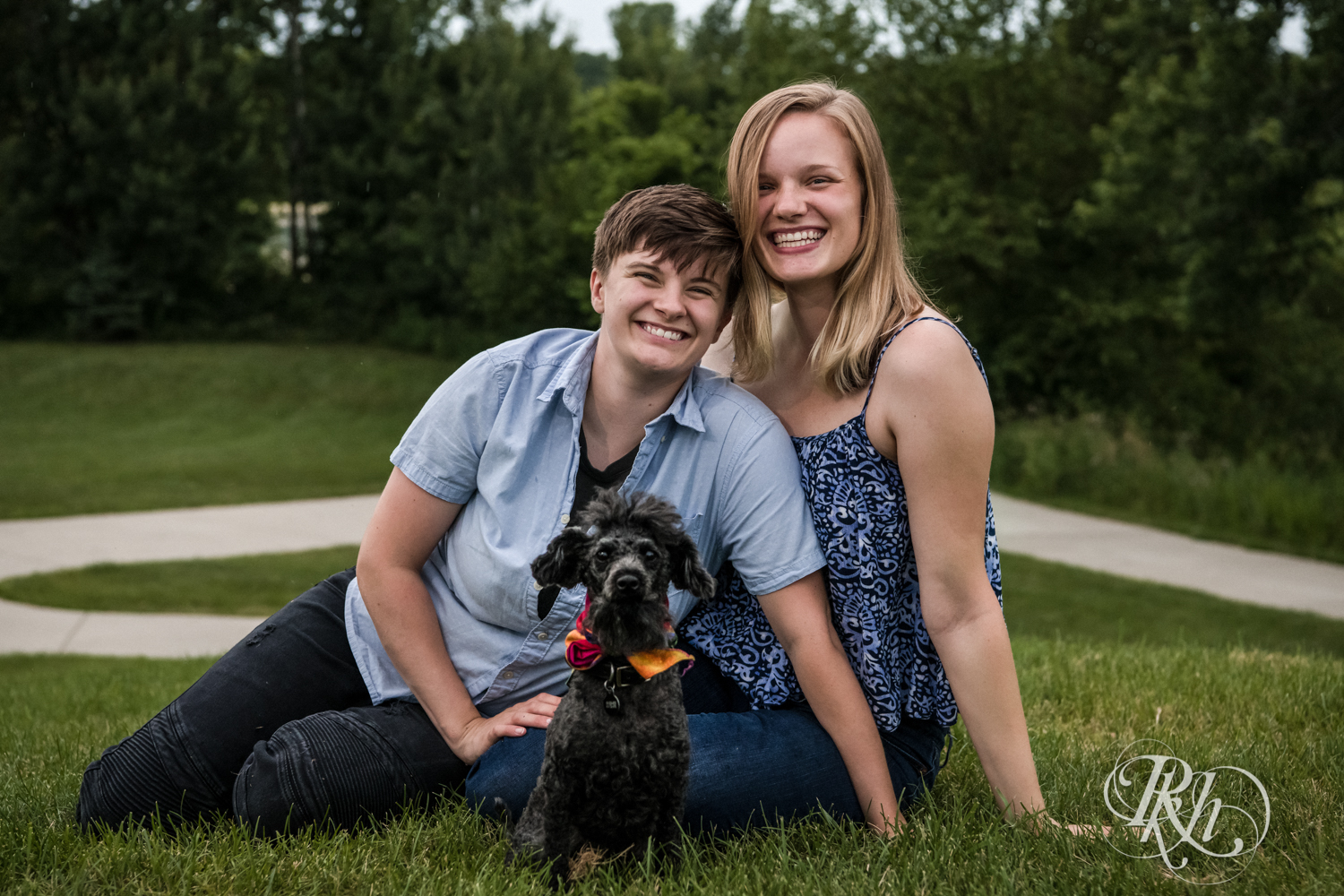 Lesbian couple smiles in the rain with their Doodle at Lebanon Hills Regional Park in Eagan, Minnesota.