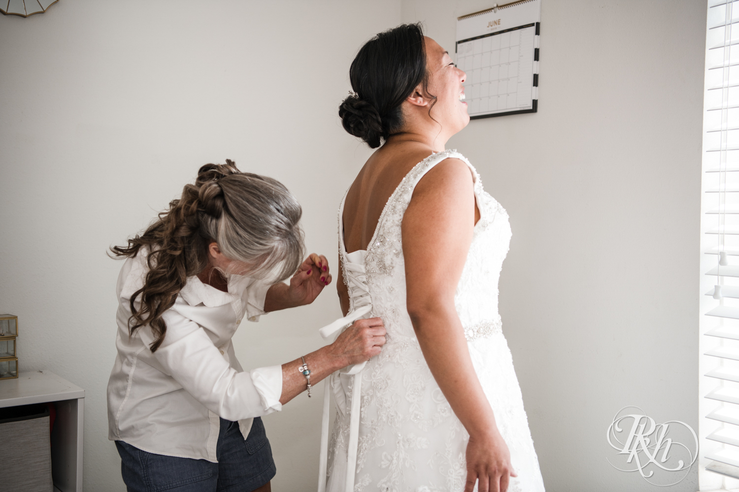 Mom helping bride get wedding dress laced up.