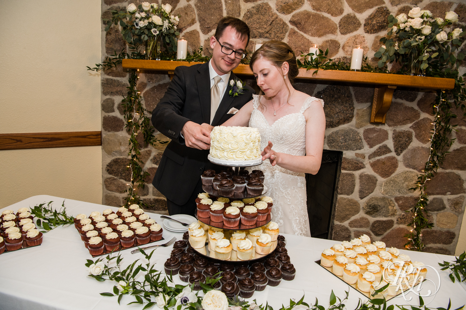 Bride and groom cut cake during wedding reception speeches at Oak Glen Golf Course in Stillwater, Minnesota.