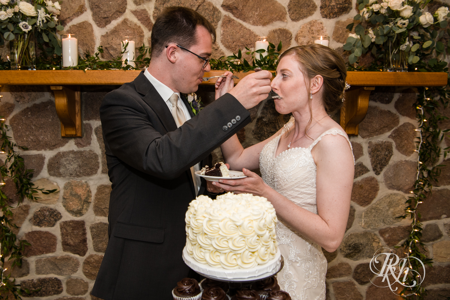 Bride and groom cut cake during wedding reception speeches at Oak Glen Golf Course in Stillwater, Minnesota.