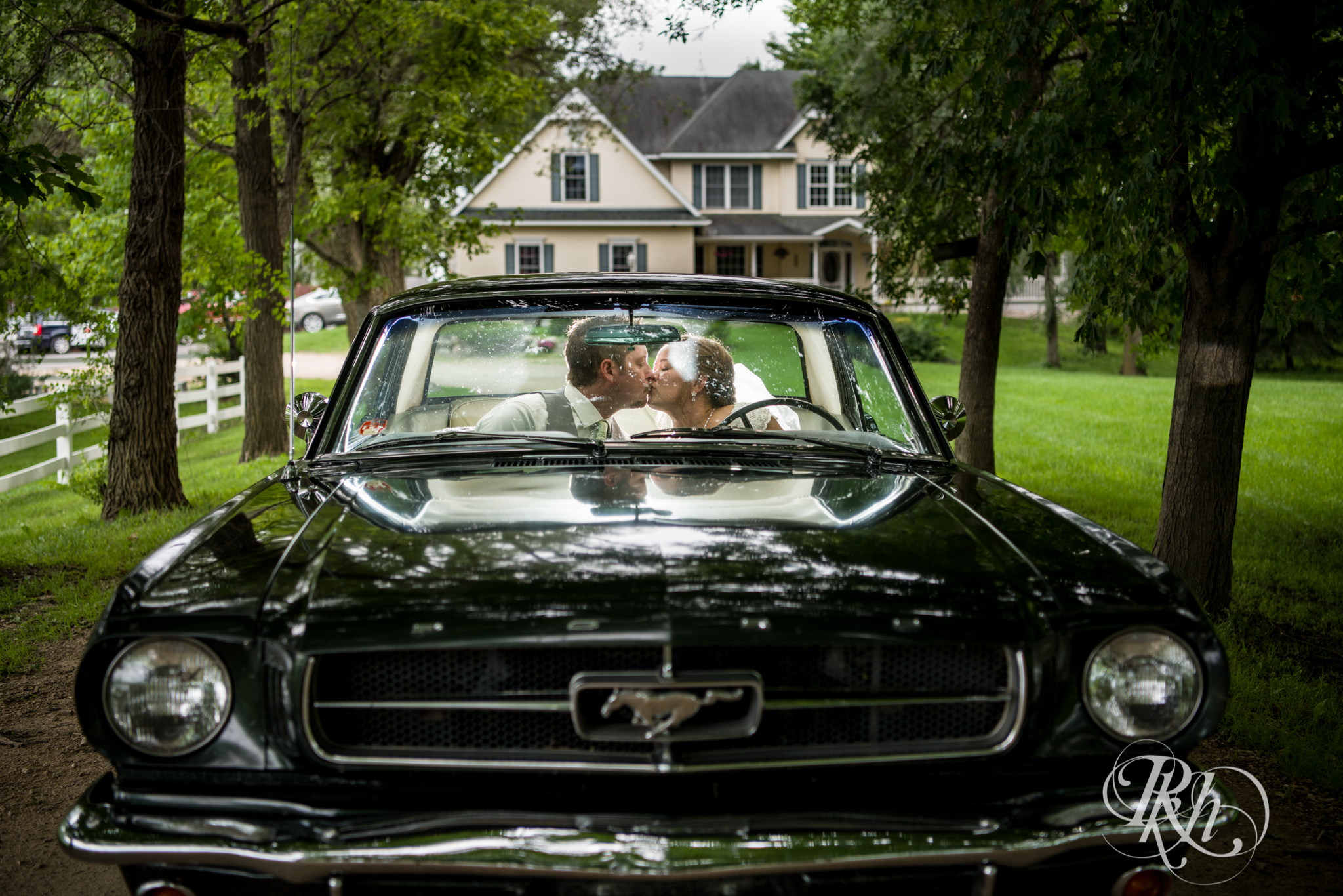 Bride and groom kissing in Mustang convertible at Next Chapter Winery in New Prague, Minnesota.
