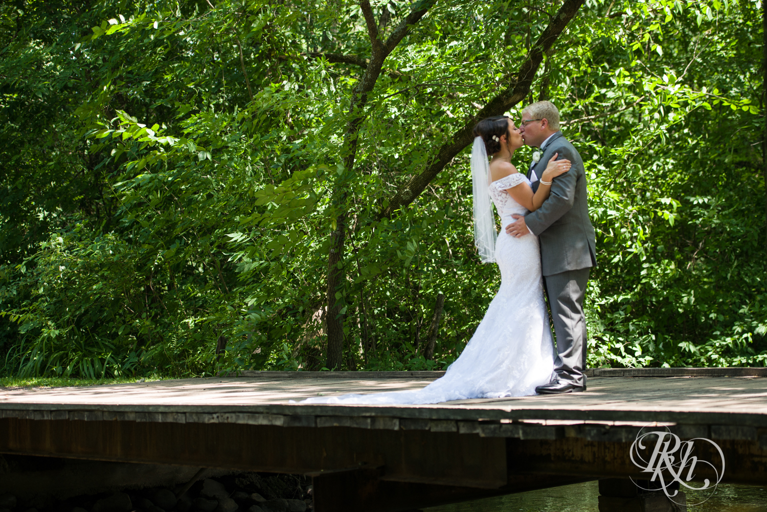 Bride and groom kiss on bridge at Creekside Farm Weddings and Events in Rush City, Minnesota.