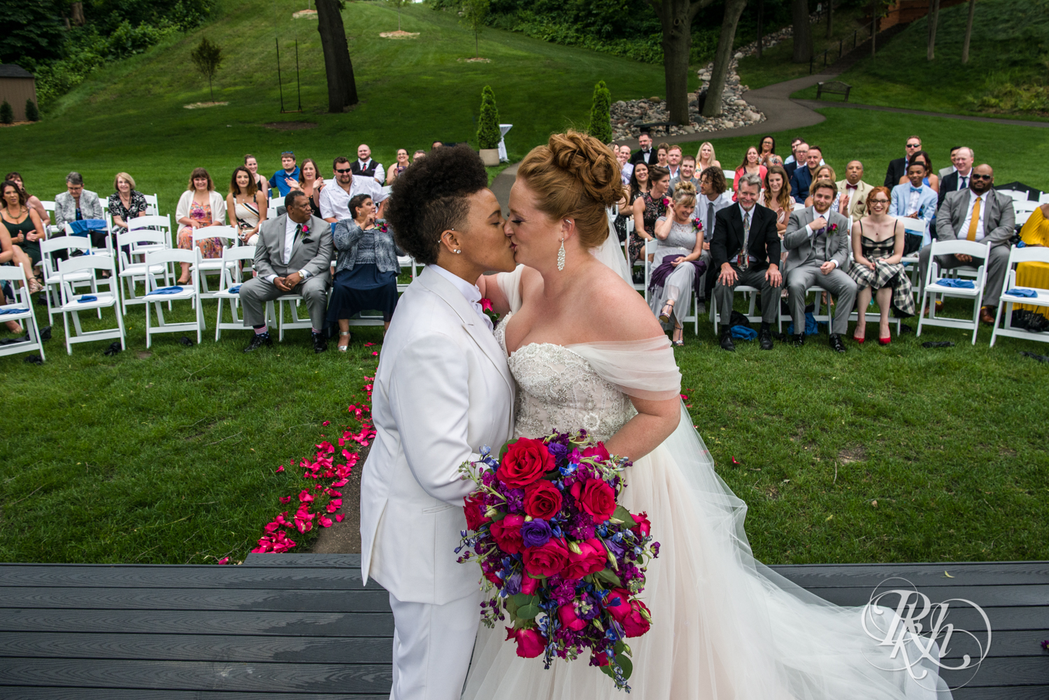 Lesbian wedding first kiss with guests in background