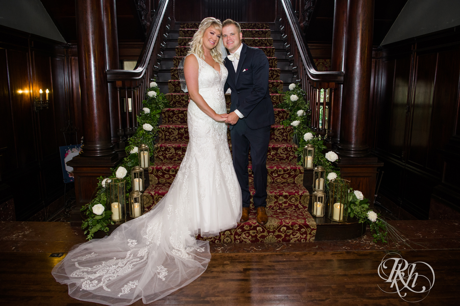 Bride and groom standing on grand staircase with candles at the Semple Mansion in Minneapolis, Minnesota.