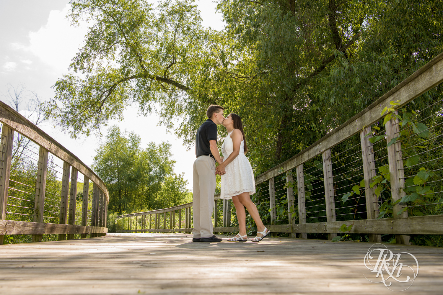 Man in black shirt and woman in white dress kiss at Lebanon Hills Regional Park in Eagan, Minnesota.