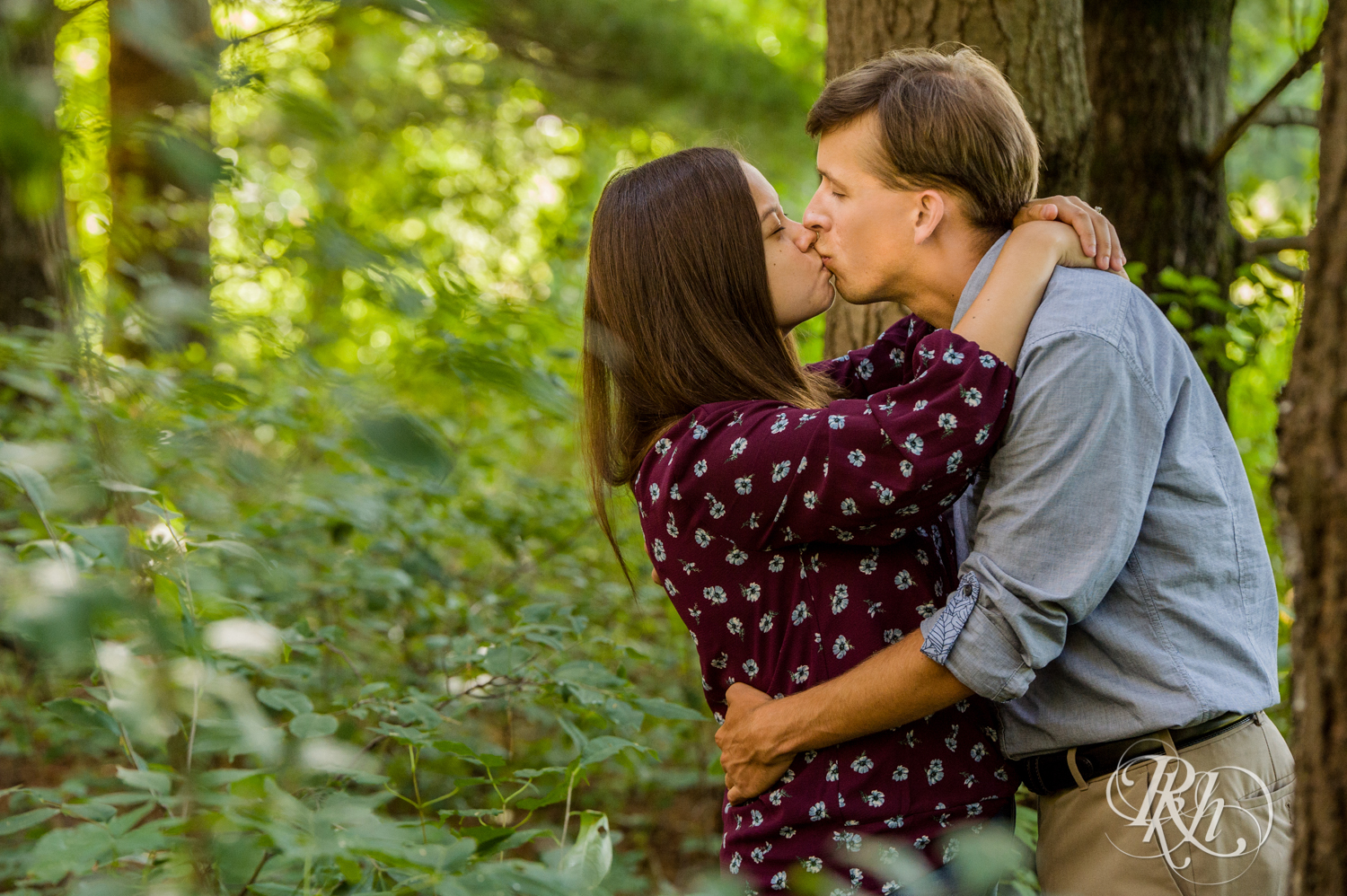 Man in denim and woman in jeans kiss at Lebanon Hills Regional Park in Eagan, Minnesota.