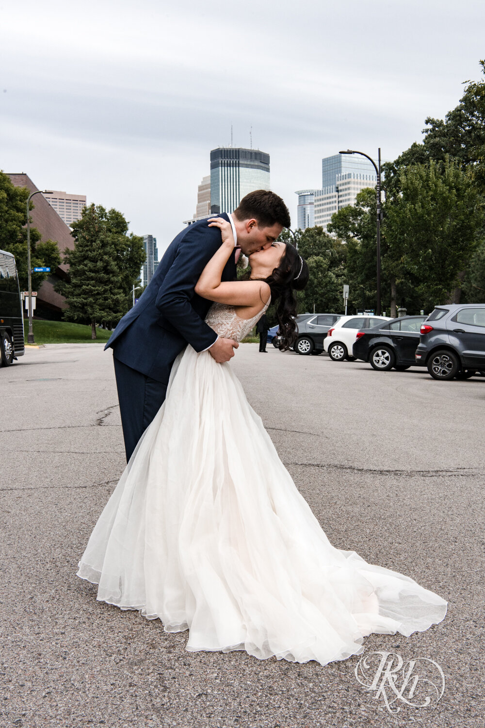 Asian bride and groom dip and kiss in Loring Park in Minneapolis, Minnesota.