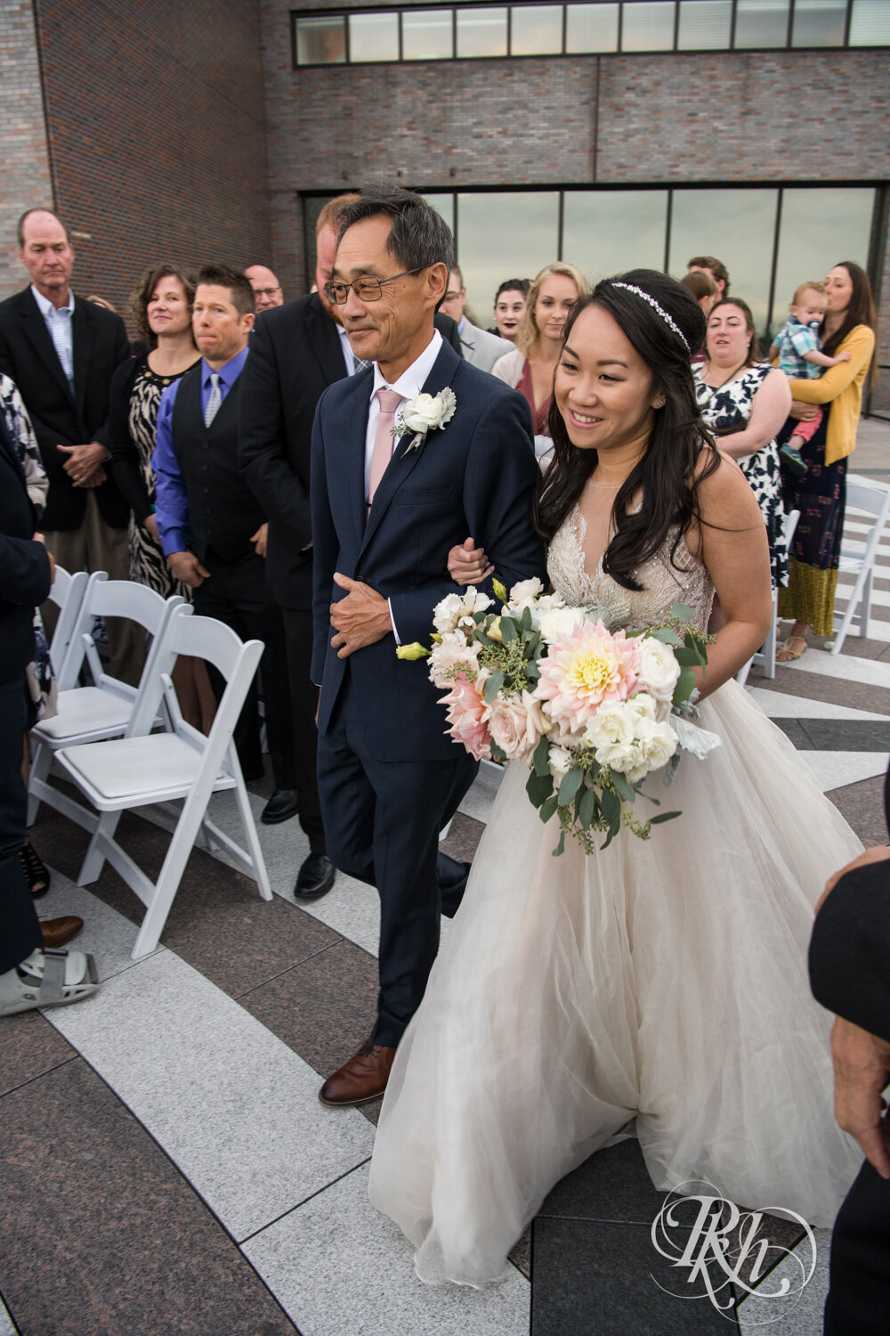 Asian bride walks down the aisle with dad on rooftop of Walker Art Center in Minneapolis, Minnesota. 