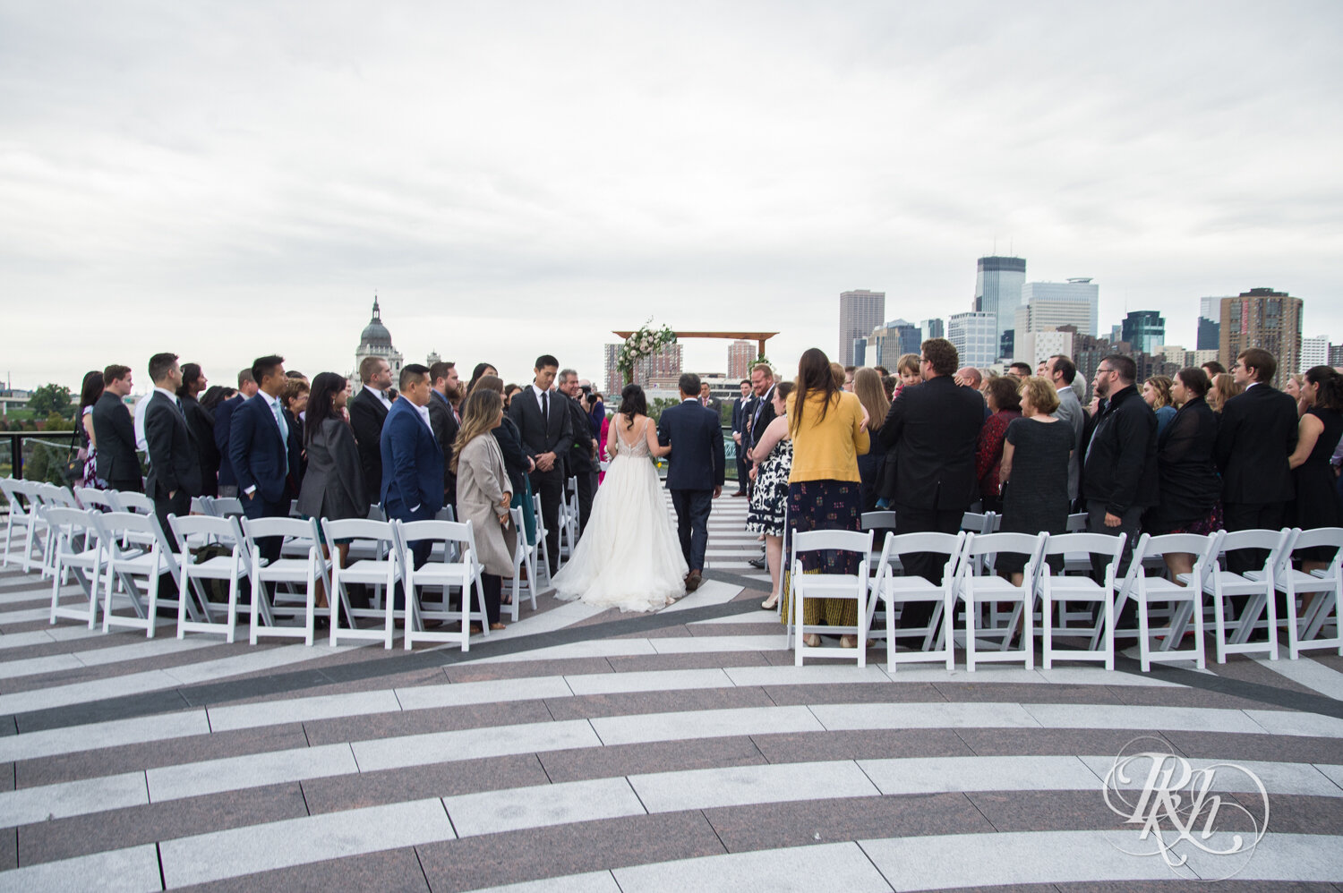 Asian bride walks down the aisle with dad on rooftop of Walker Art Center in Minneapolis, Minnesota. 