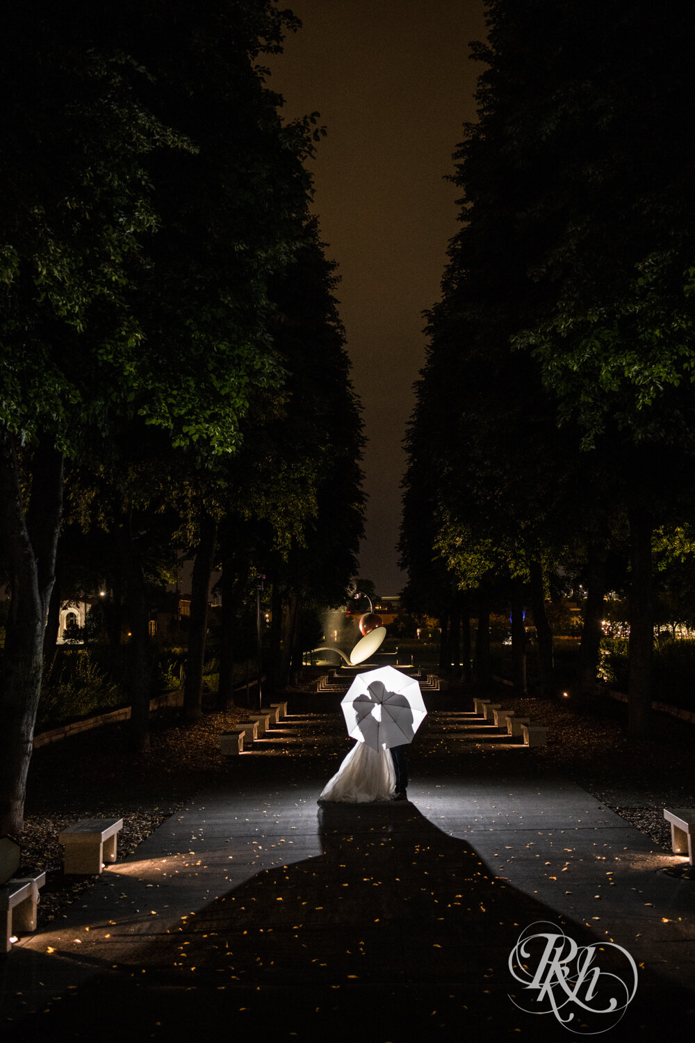 Asian bride and groom kiss in front Spoonbridge and Cherry in Sculpture Garden in Minneapolis, Minnesota at night.