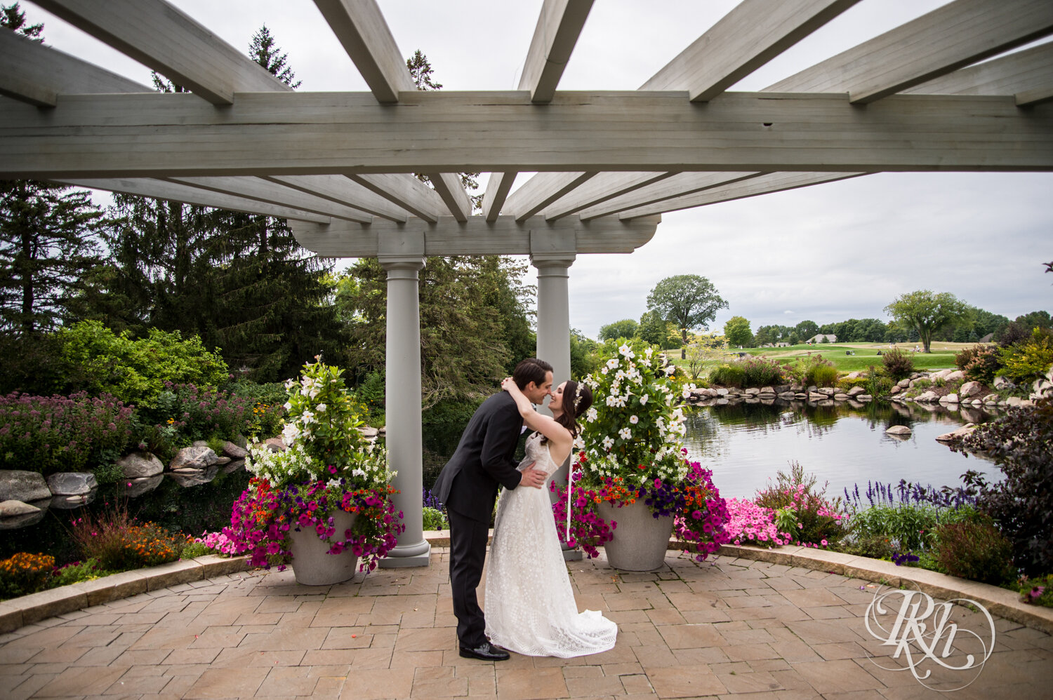 Bride and groom smile amongst colorful flowers at Olympic Hills Golf Club in Eden Prairie, Minnesota.