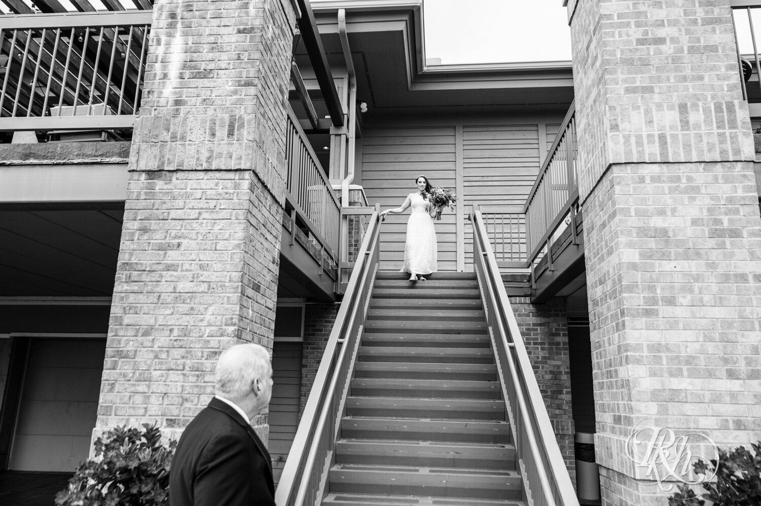 Bride walks down stairs to wedding ceremony at Olympic Hills Golf Club in Eden Prairie, Minnesota.