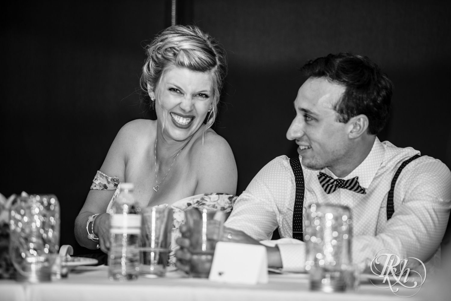 Bride and groom laugh during speeches at wedding reception at Brookview Golf Course in Golden Valley, Minnesota.