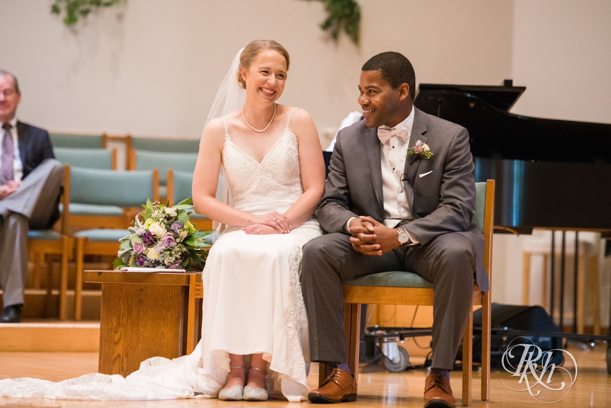 Black groom and white bride laugh during wedding ceremony at church in Richfield, Minnesota.