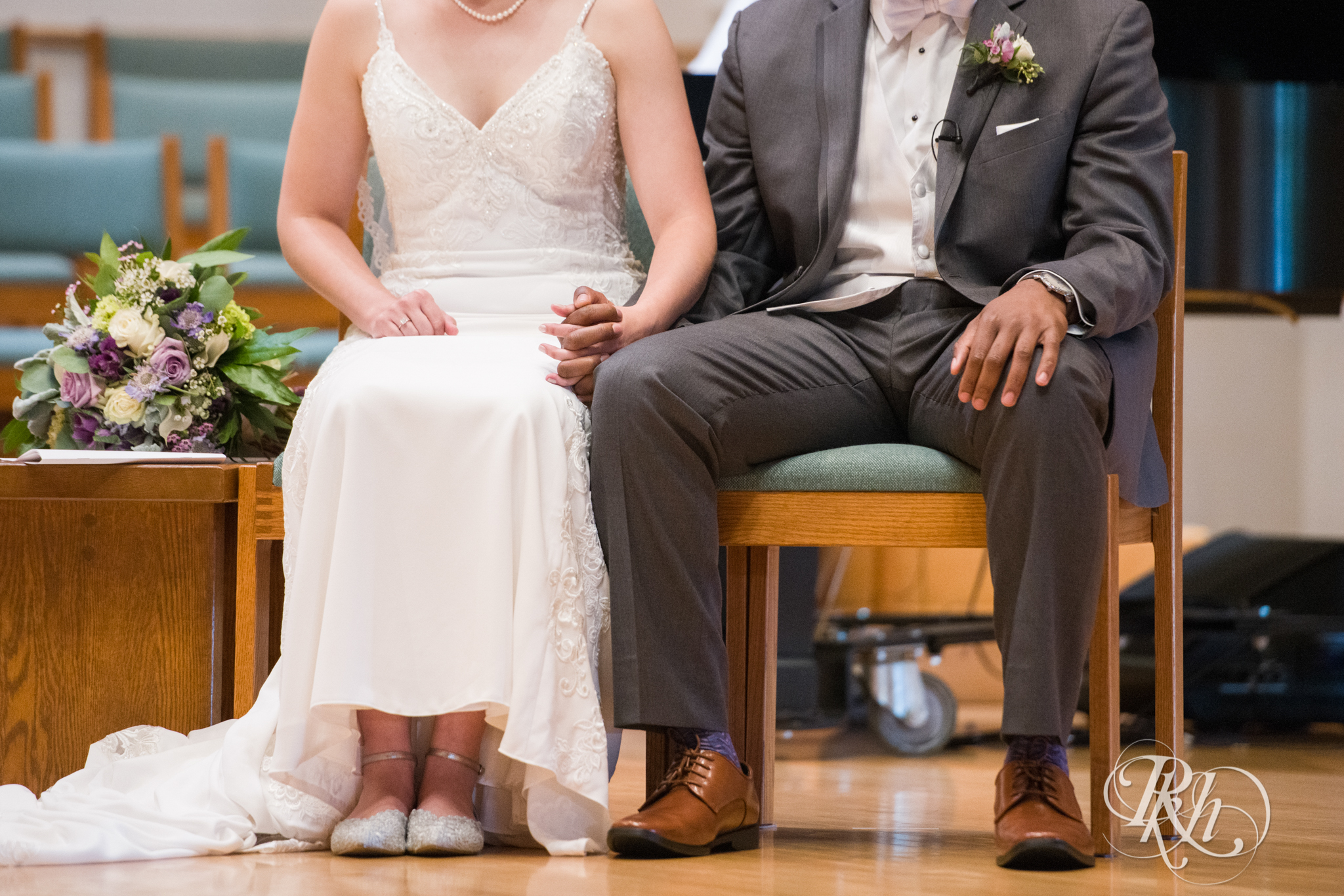 Black groom and white bride hold hands during wedding ceremony at church in Richfield, Minnesota.