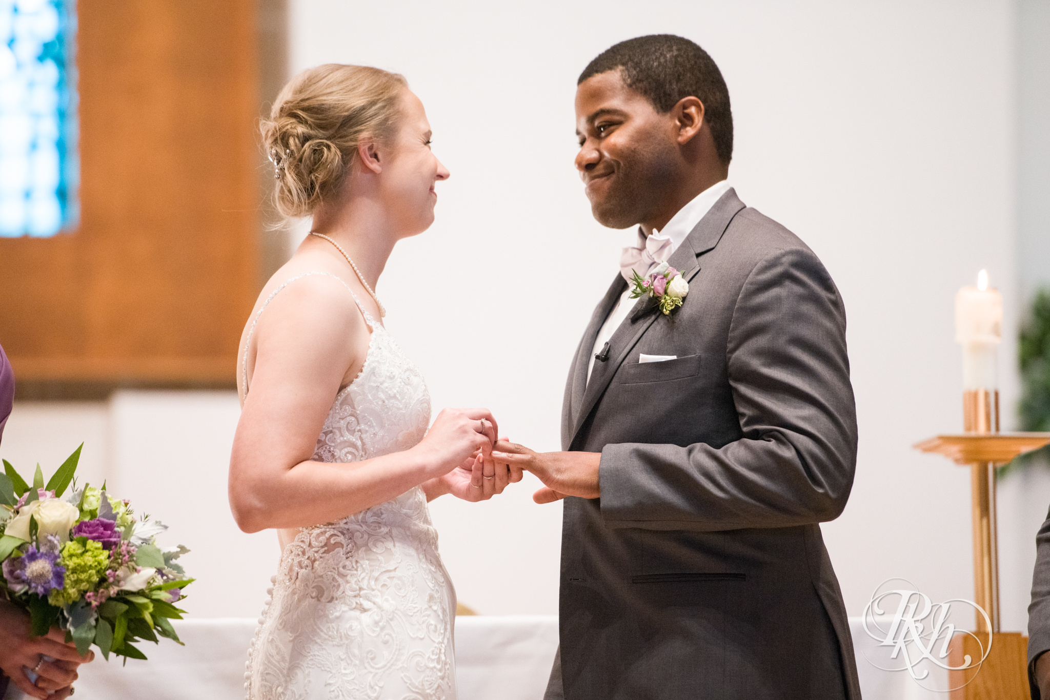 Black groom and white bride exchange rings during wedding ceremony at church in Richfield, Minnesota.