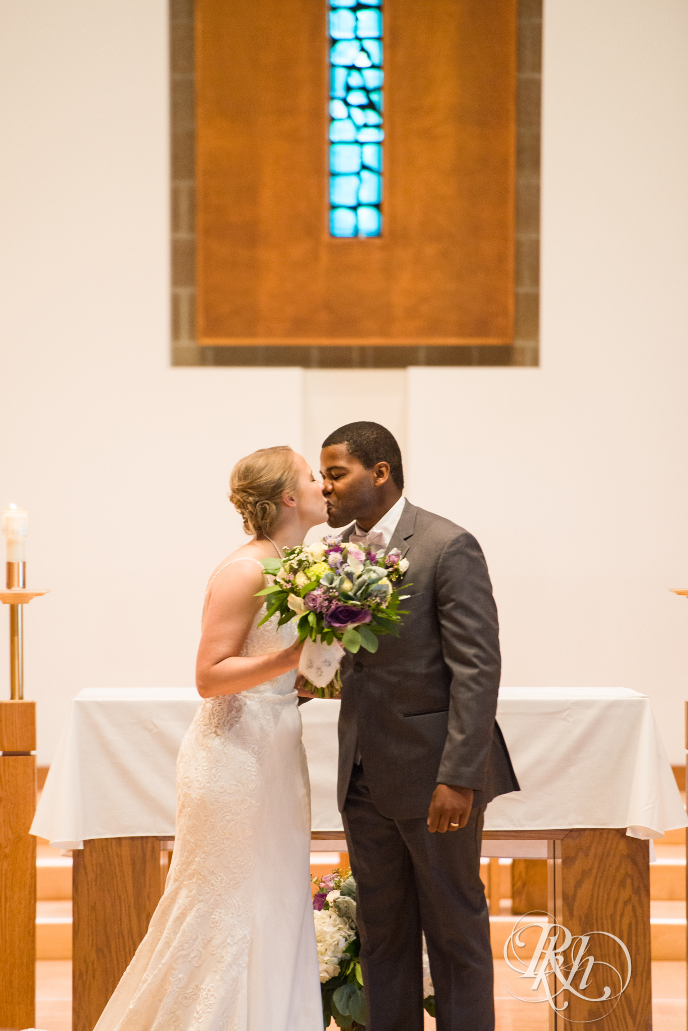 Black groom and white bride kiss during wedding ceremony at church in Richfield, Minnesota.