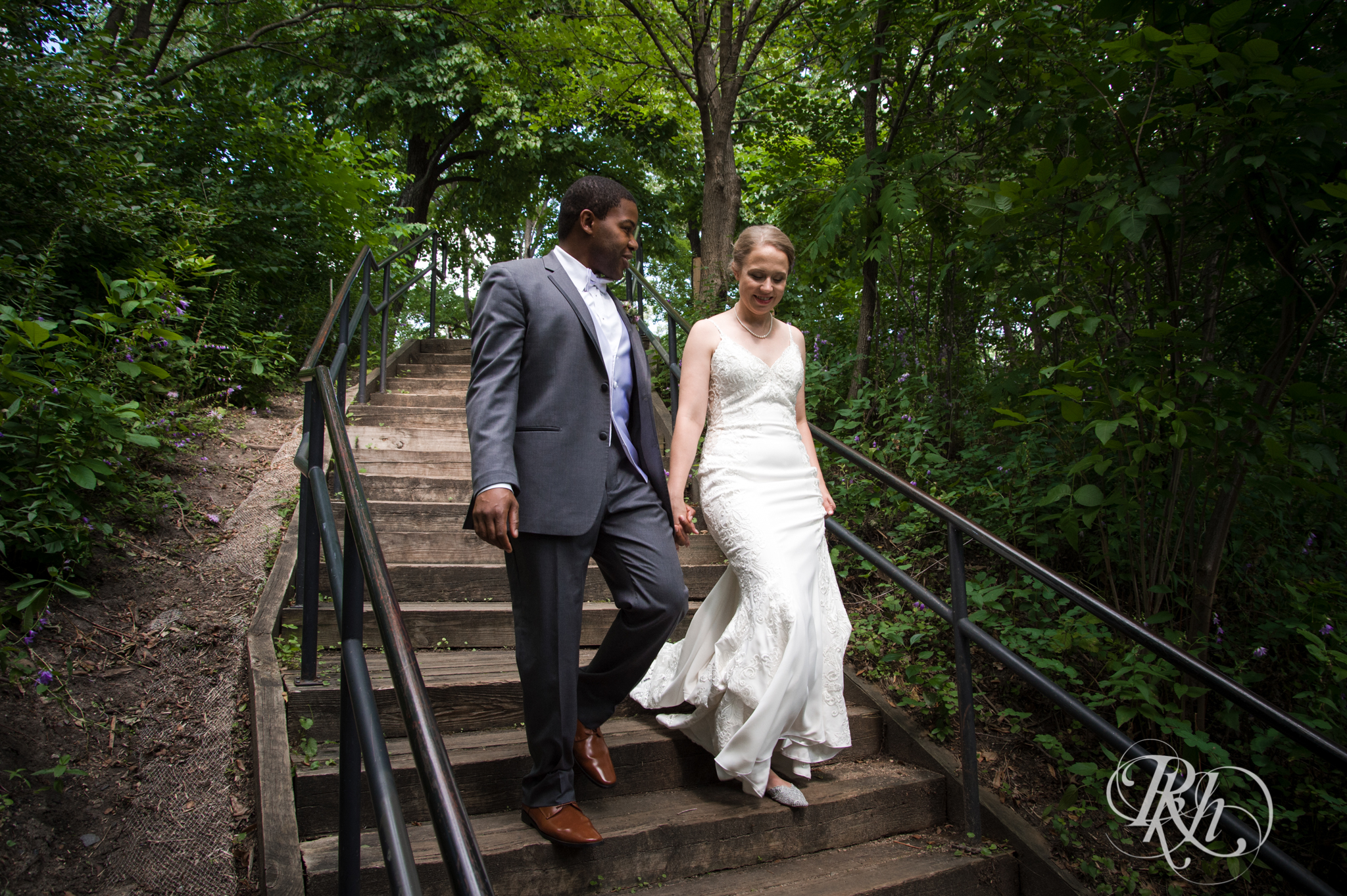 Black groom and white bride walk down stairs at Witches Hat in Saint Paul, Minnesota.