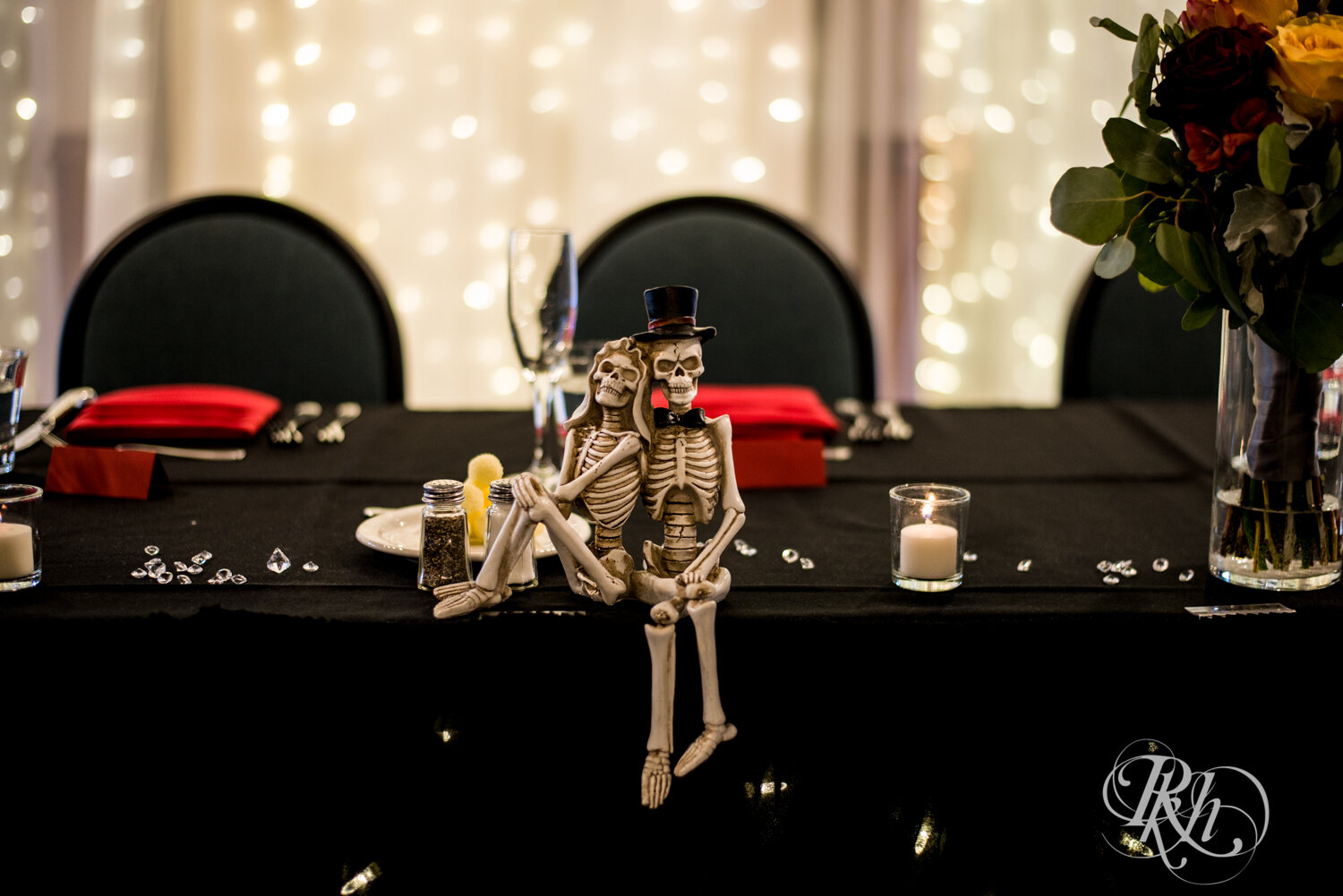 Indoor wedding reception setup with black tablecloth and skeleton statues at Rockwoods in Otsego, Minnesota.