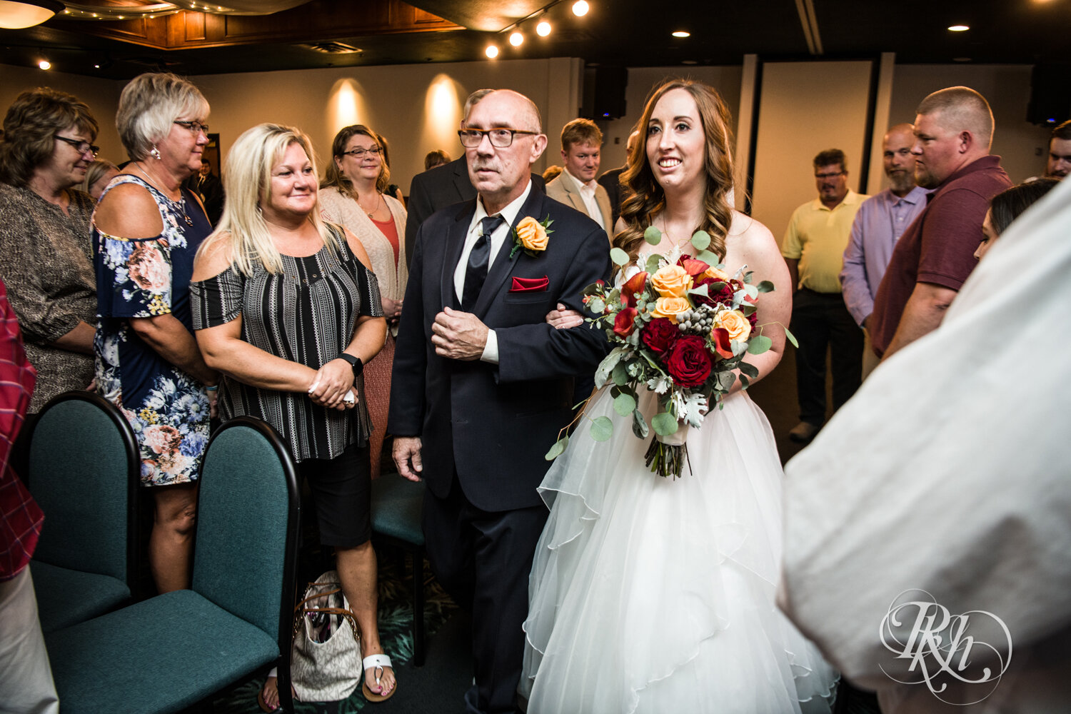 Bride walks down the aisle with dad at indoor wedding ceremony at Rockwoods in Otsego, Minnesota.