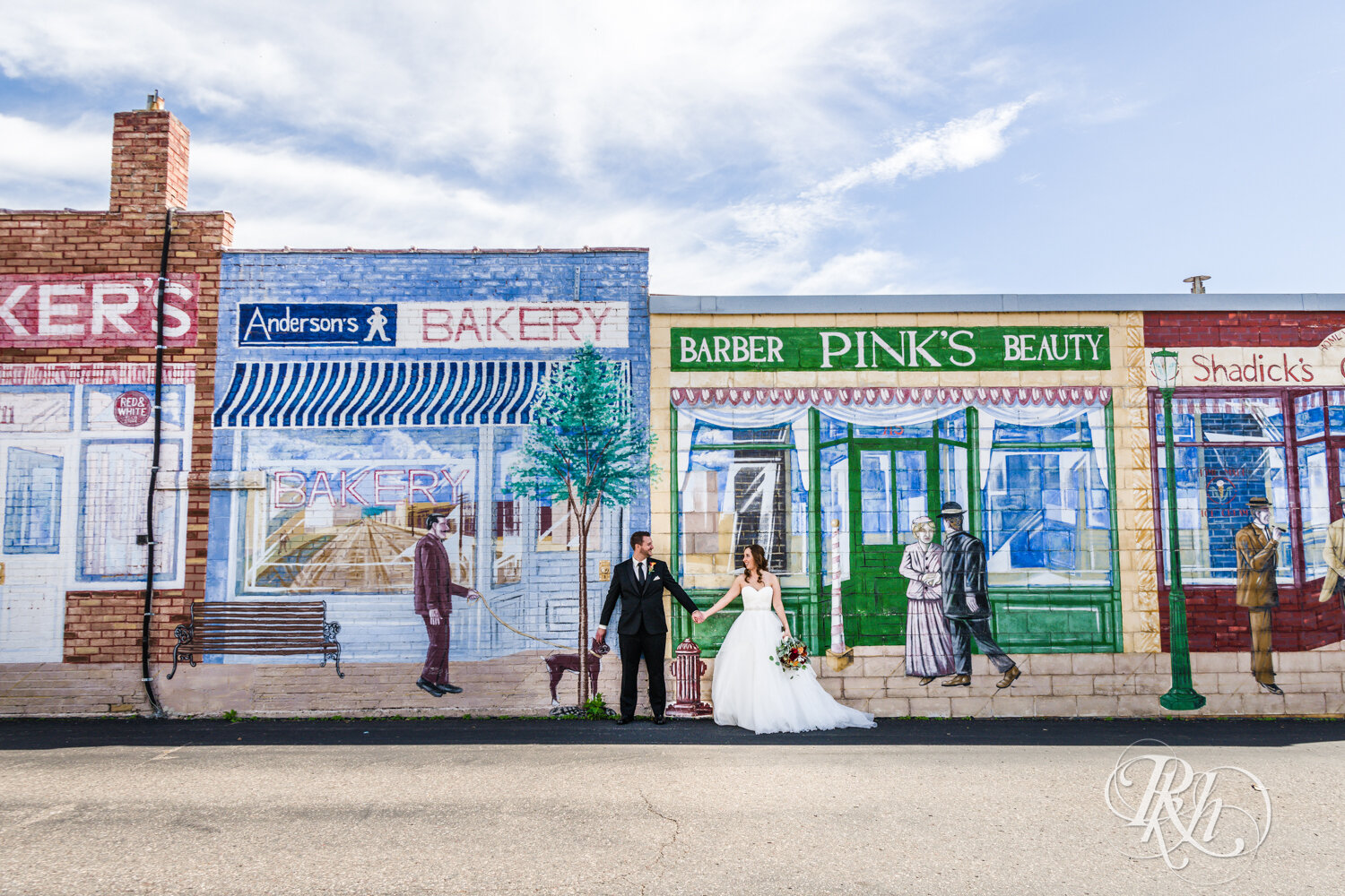 Bride and groom kissing in front of mural in Otsego, Minnesota on sunny wedding day.